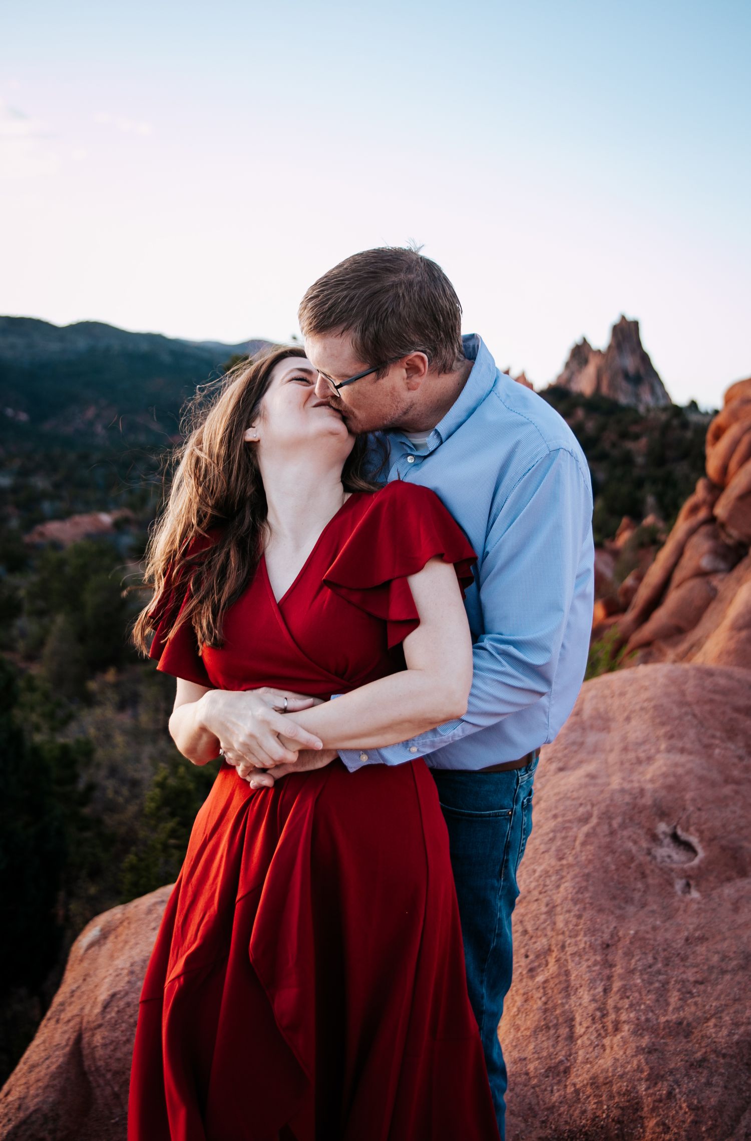 A romantic embrace captured at sunset with dramatic red rocks in the background.
