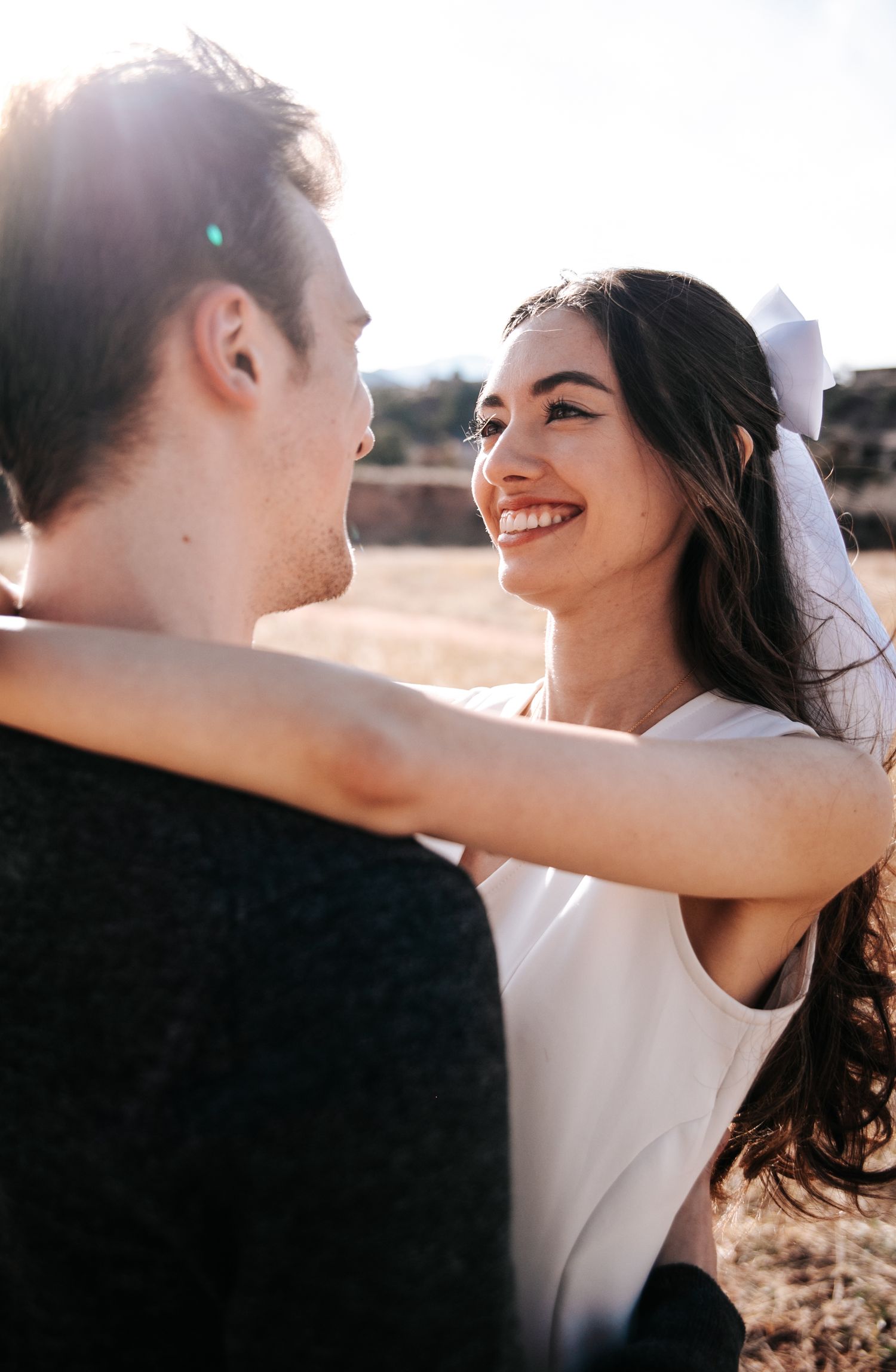 A sunlit outdoor portrait capturing a tender romantic moment between a couple.