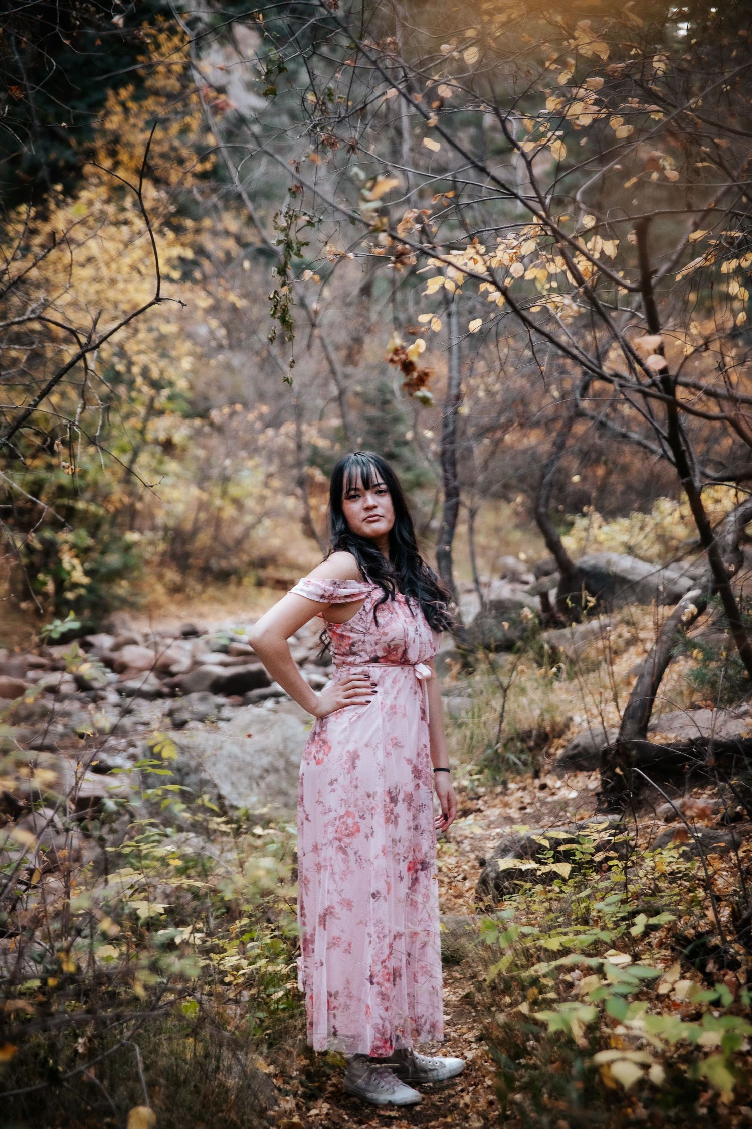A feminine portrait in a floral pink dress amid autumn scenery.