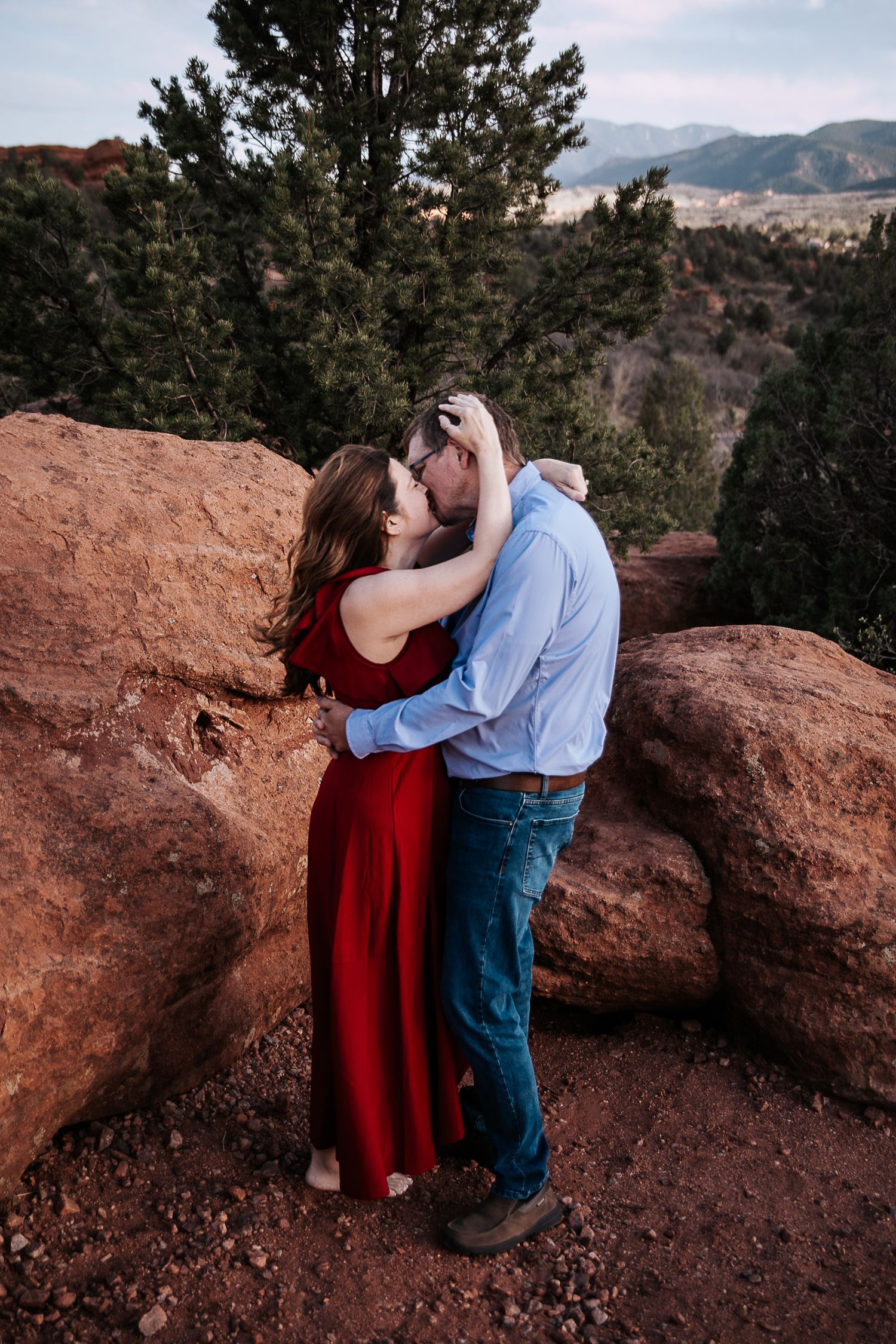 A tender embrace photographed against a backdrop of red rocks and mountain scenery.