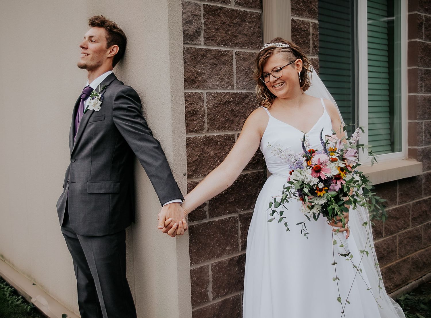 Bride and groom holding hands around a corner during Kansas City wedding from Colorado Springs wedding photographer Jasmine Morse