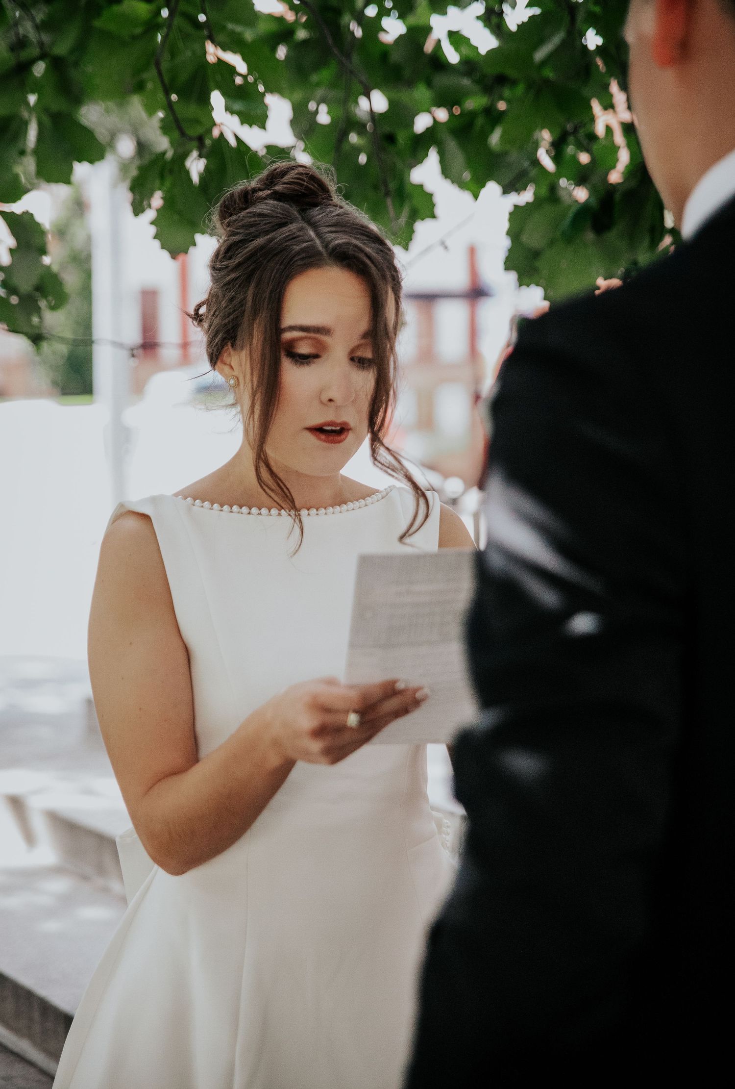Intimate outdoor wedding ceremony moment with a bride in white dress reading vows at Colorado Springs courthouse wedding.
