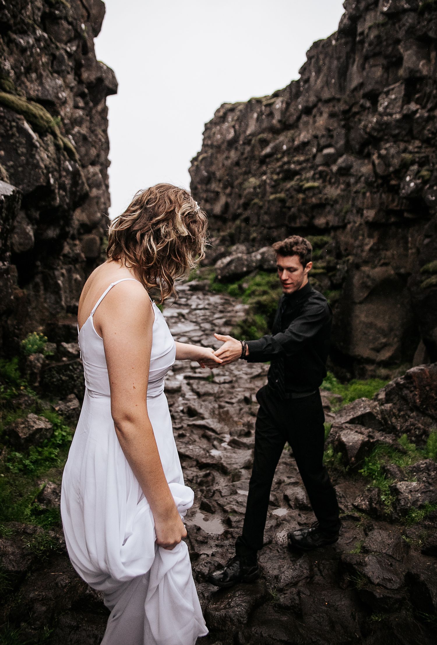 Man helping bride in Öxarárfoss in Iceland during elopement shoot