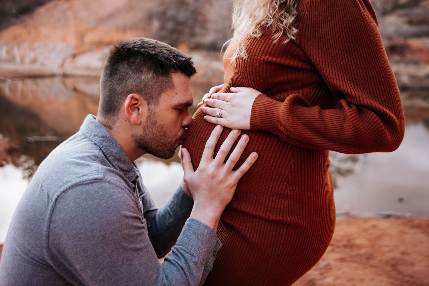 Intimate maternity moment captured against red rocks as a couple celebrates their upcoming arrival.