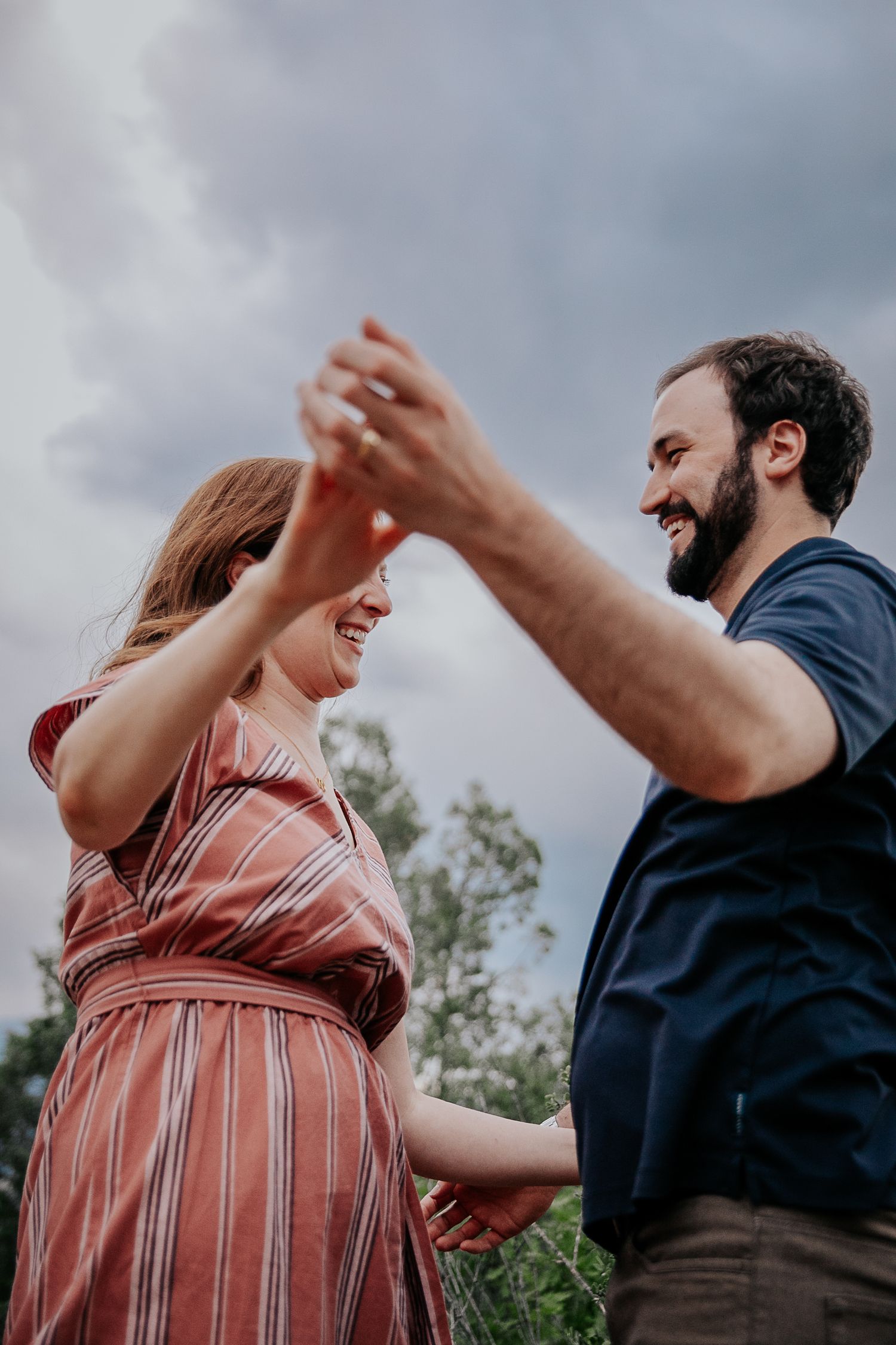 A joyful couple laughs and dances together during an outdoor photo session.