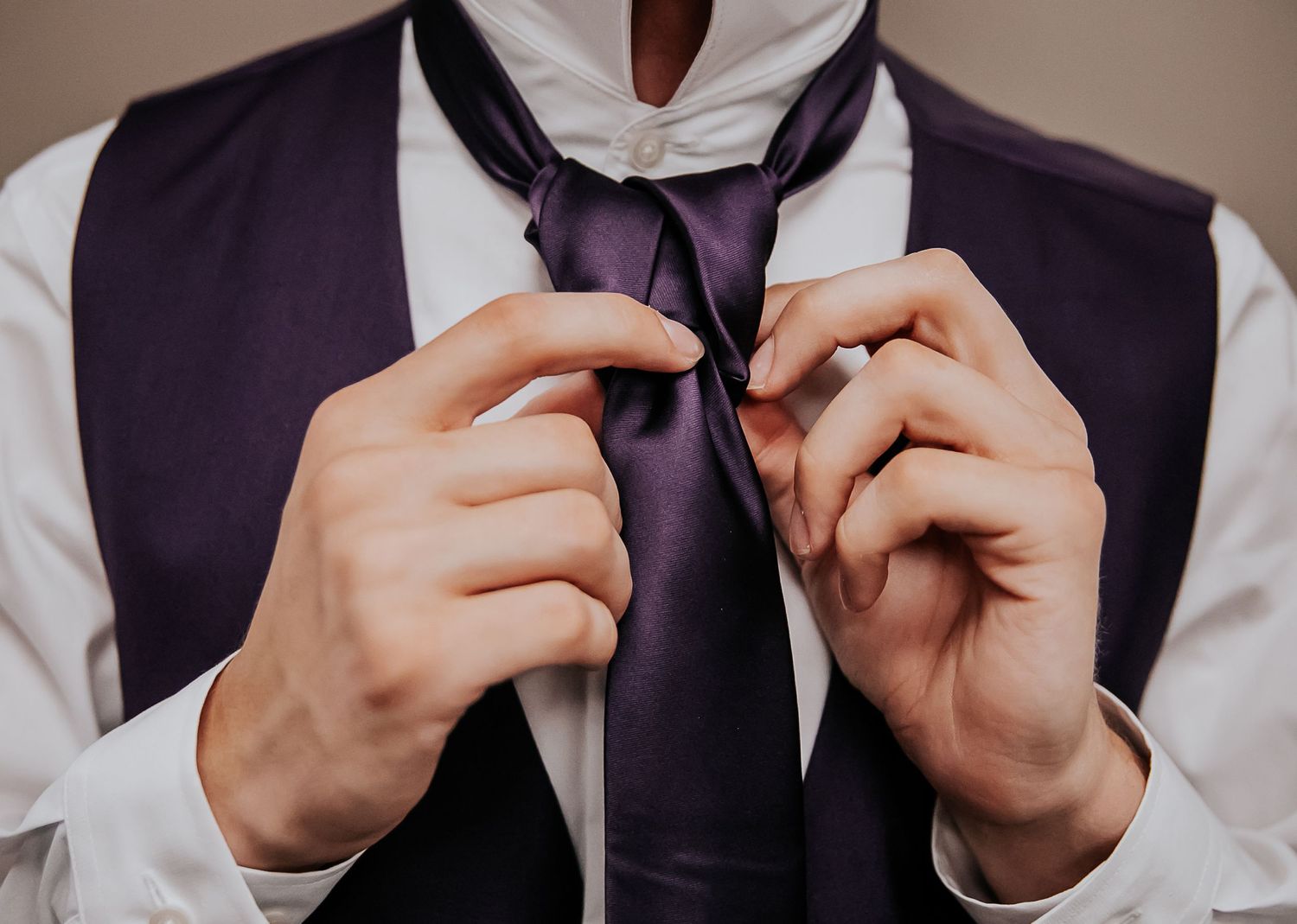 Hands adjusting a formal black bow tie against a white shirt.