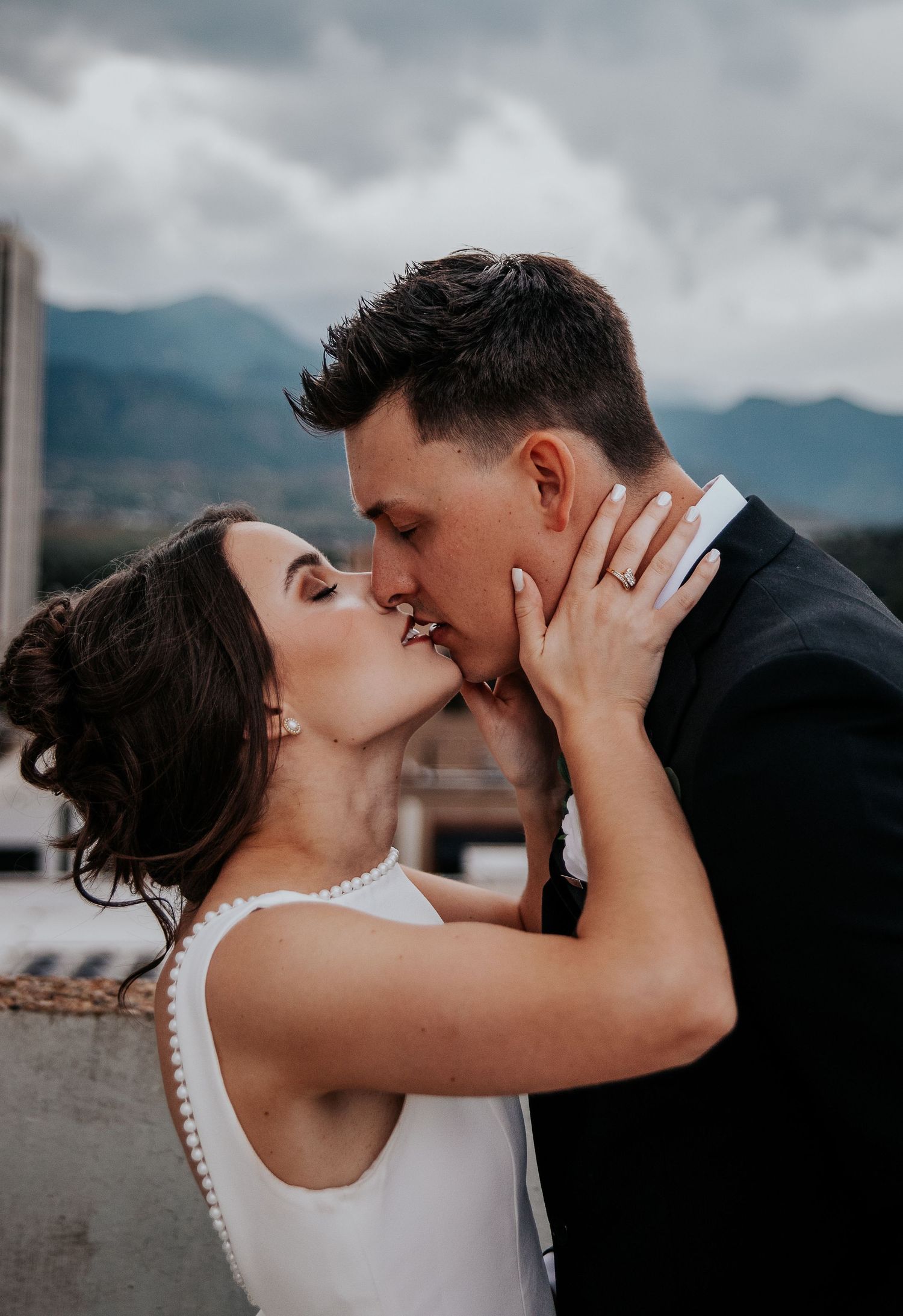 Romantic wedding couple sharing intimate moments against a mountain backdrop.