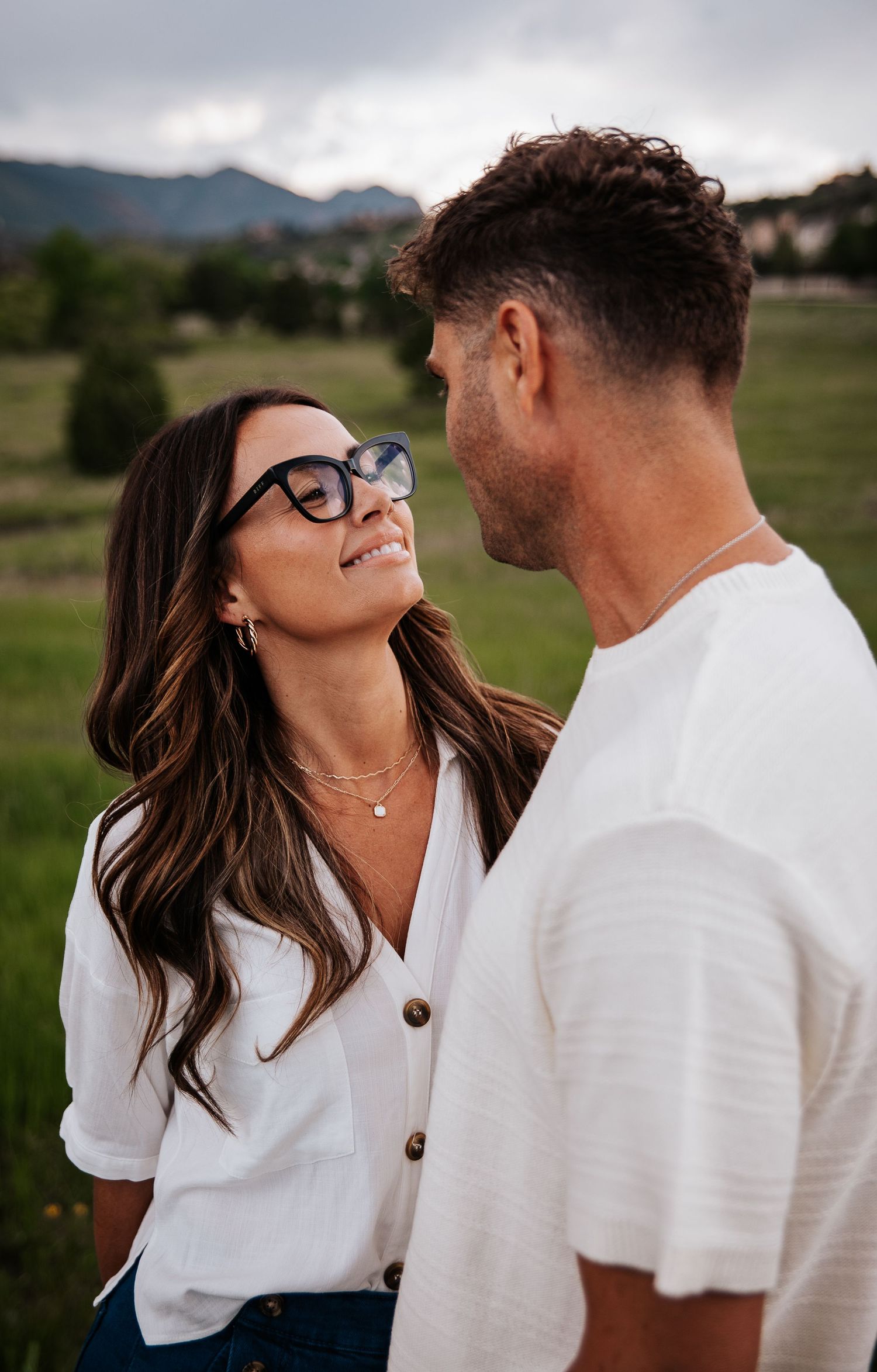 Romantic couple moments captured against a mountain backdrop while wearing coordinated white outfits at Ute Valley Park in Colorado Springs