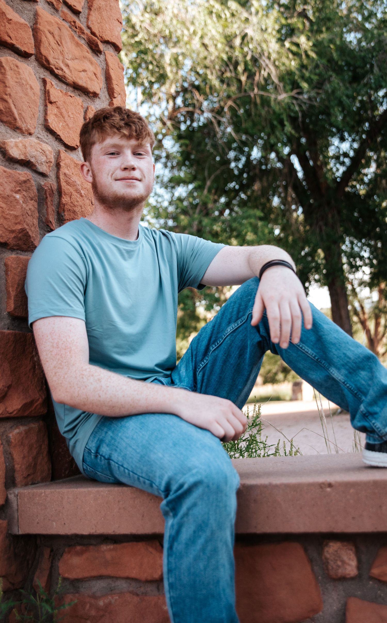 Casual outdoor portraits on a red stone bench wearing a blue t-shirt.