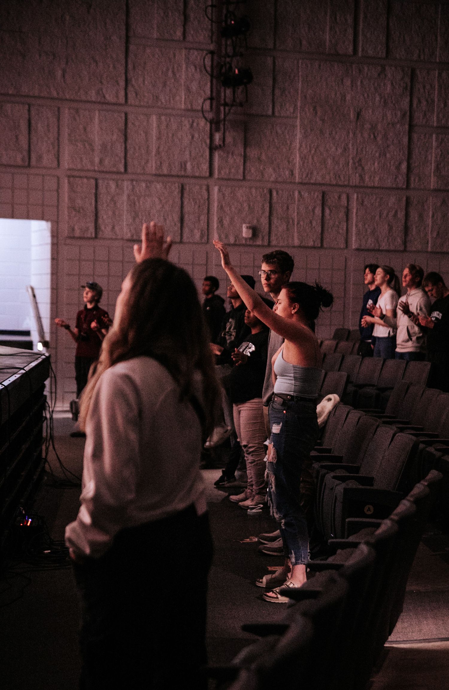 Crowd in a theater auditorium with hands raised during an interactive performance.