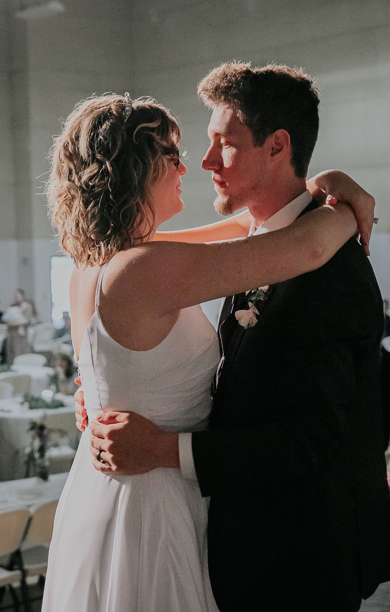 Newlyweds share intimate first dance moment at indoor reception venue.
