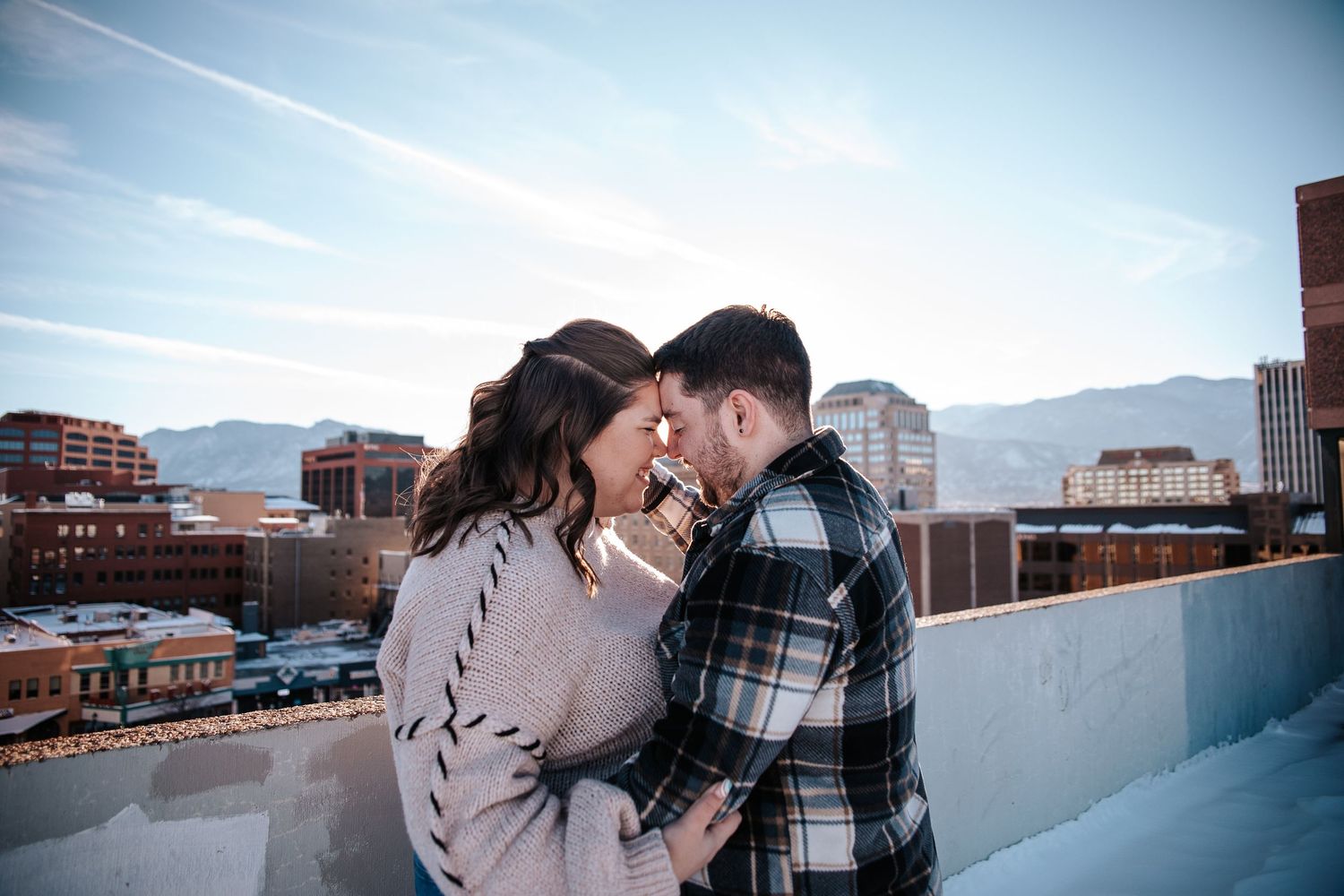 Couple nuzzles close during golden hour winter engagement photo session in Downtown Colorado Springs