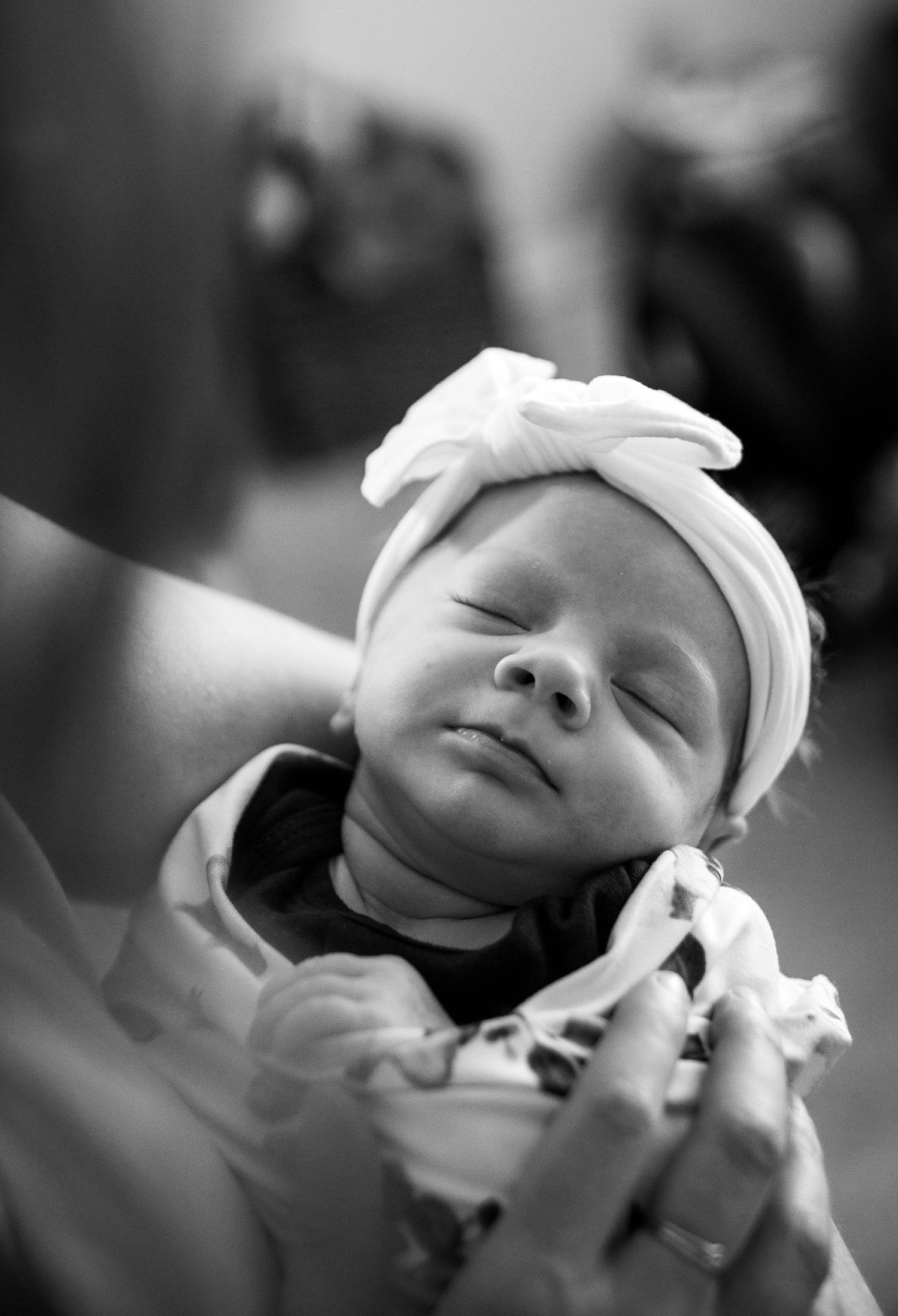 Peaceful sleeping newborn wearing white headband captured in black and white photography.