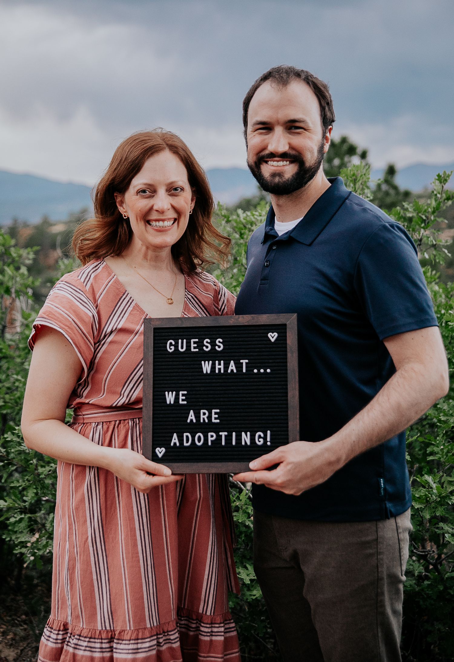 Couple holding up a sign announcing their adoption during adoption portfolio photos at Palmer Park in Colorado Springs