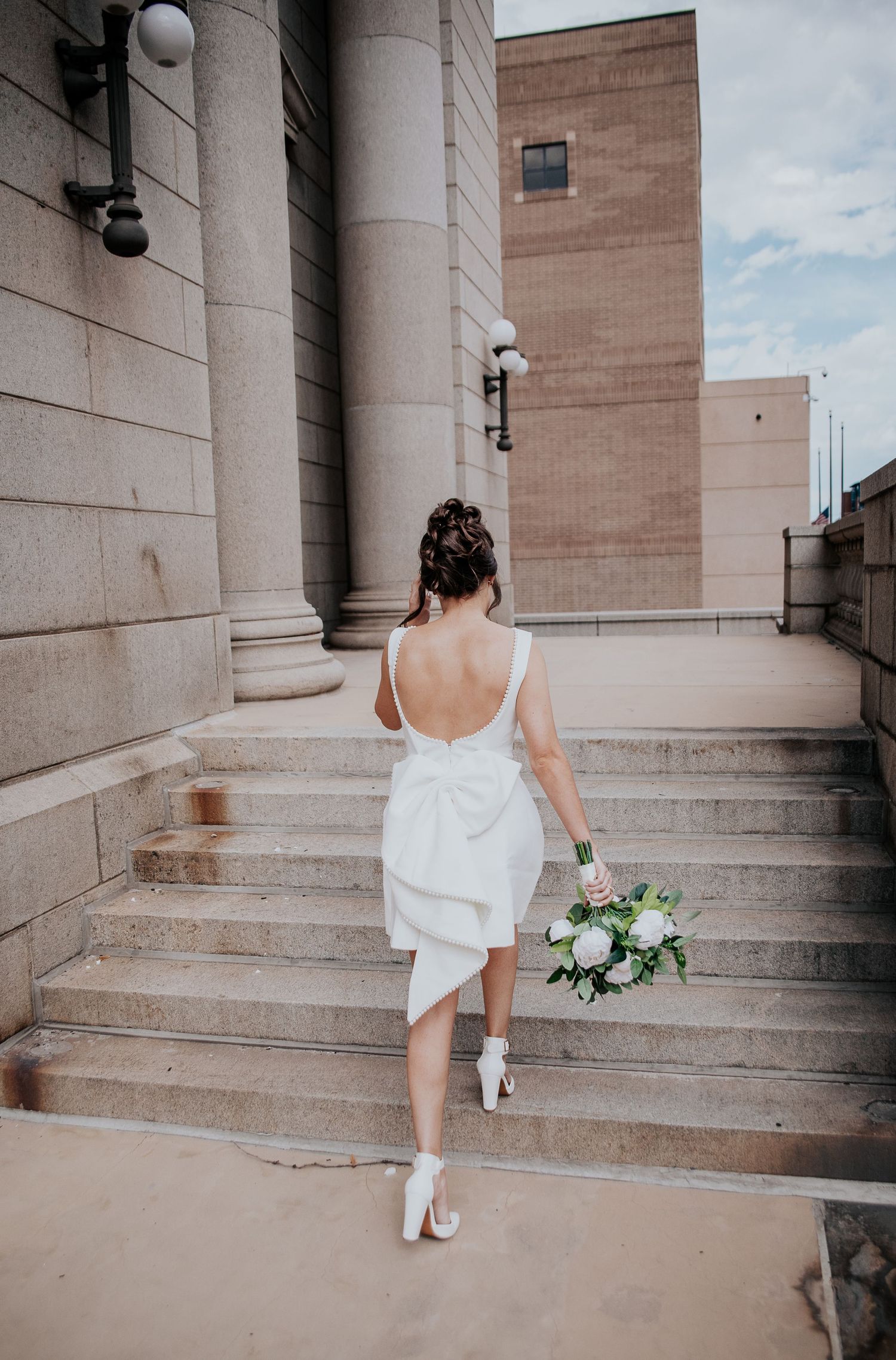 A series of photos showing someone in a white dress ascending stone steps of a classical building at Colorado Springs courthouse wedding.