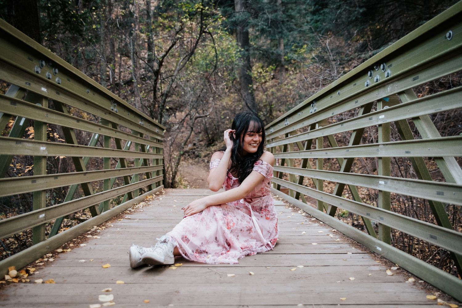 A dreamy portrait on a wooden bridge with someone in a pink floral dress.