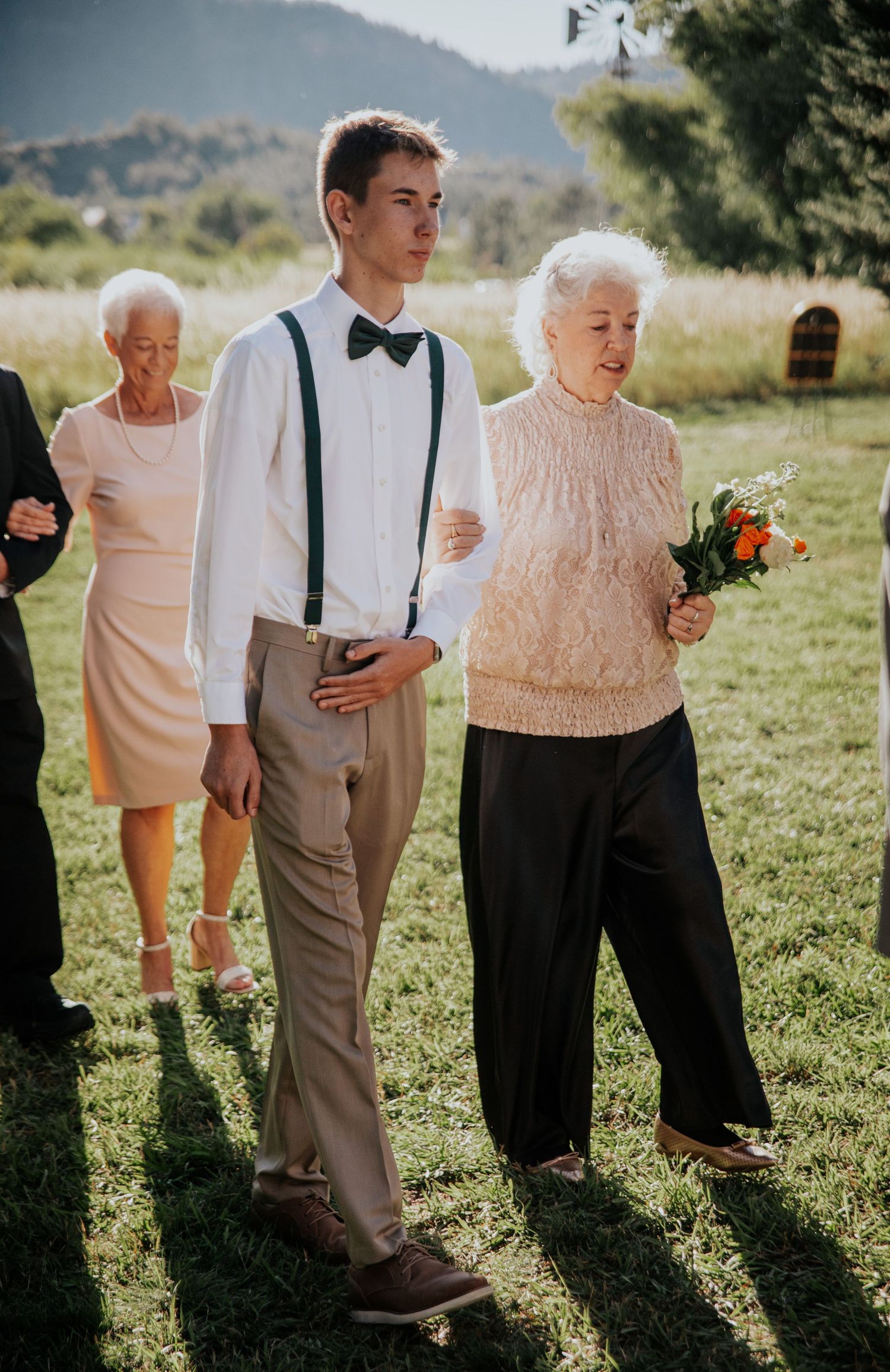 People in formal attire gathered for an outdoor wedding ceremony.