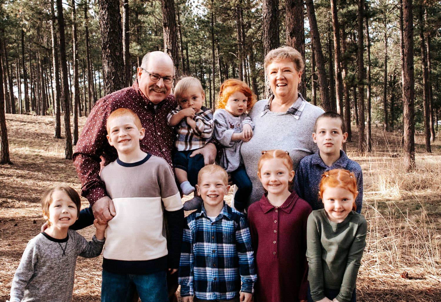 Children and adults enjoying a casual photo session in a wooded setting.
