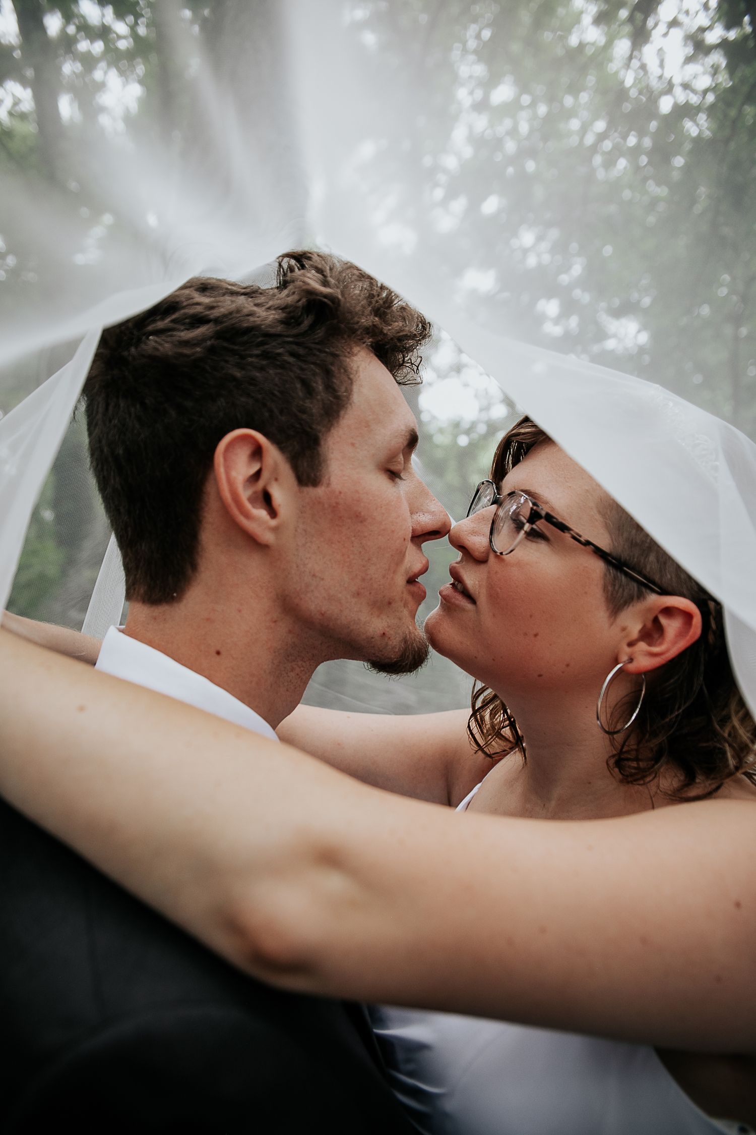 An intimate embrace captured with dreamy fog and forest backdrop.