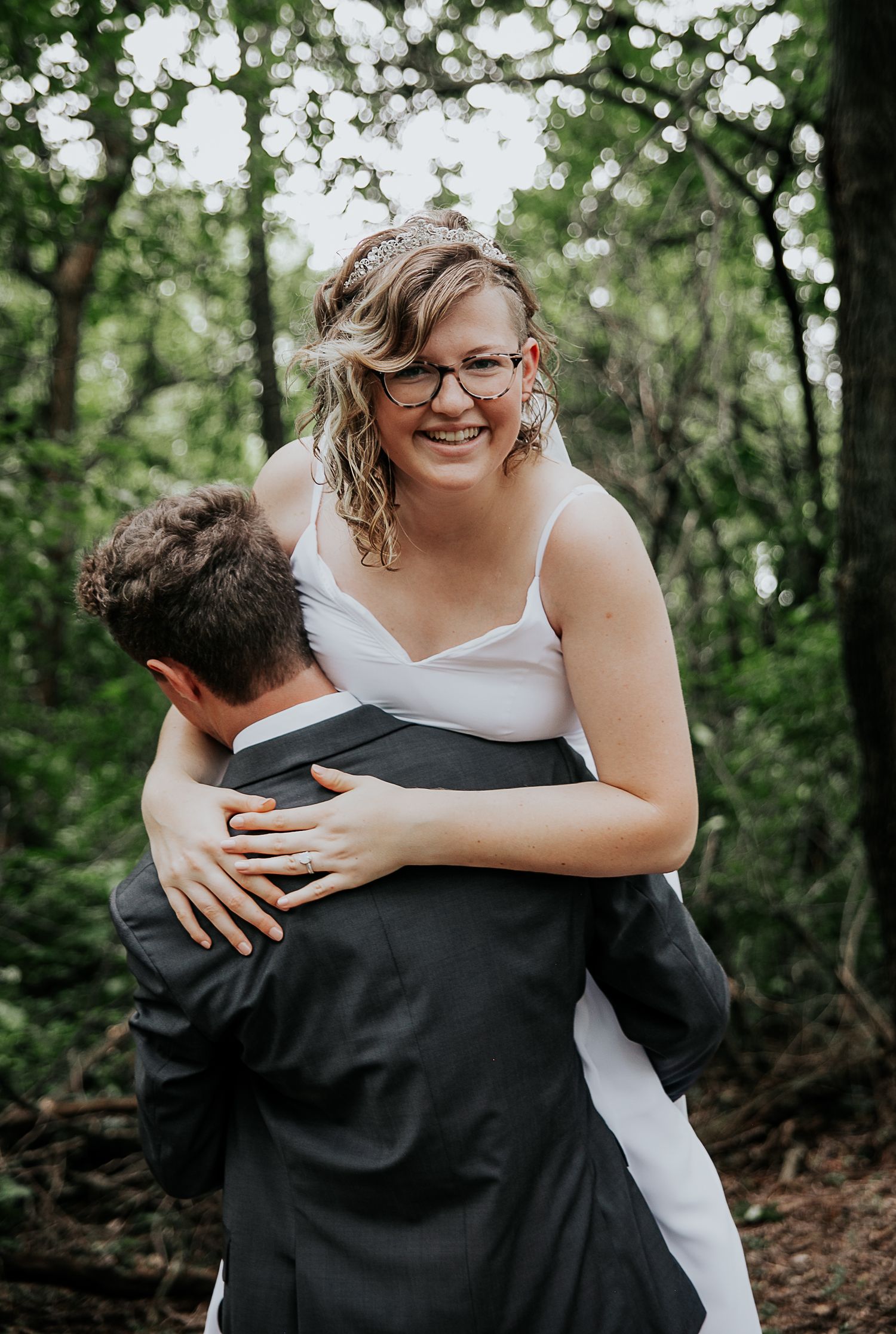 A joyful moment captured during a wedding photoshoot in a lush forest setting.