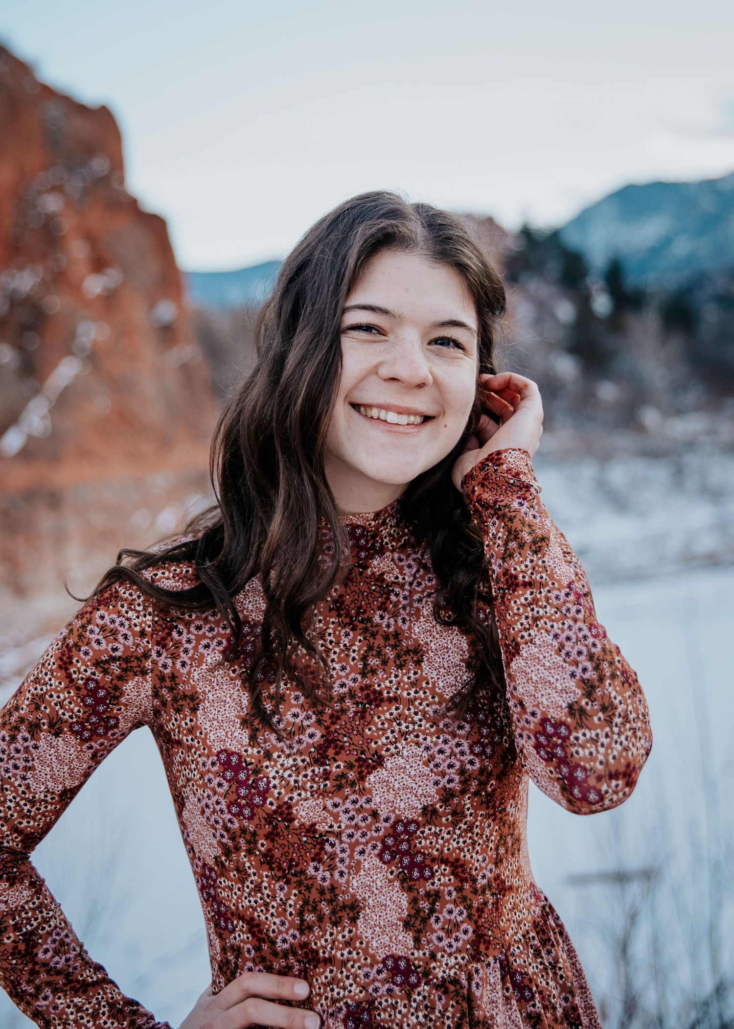 Playful portrait series featuring a floral print dress in winter mountain setting.