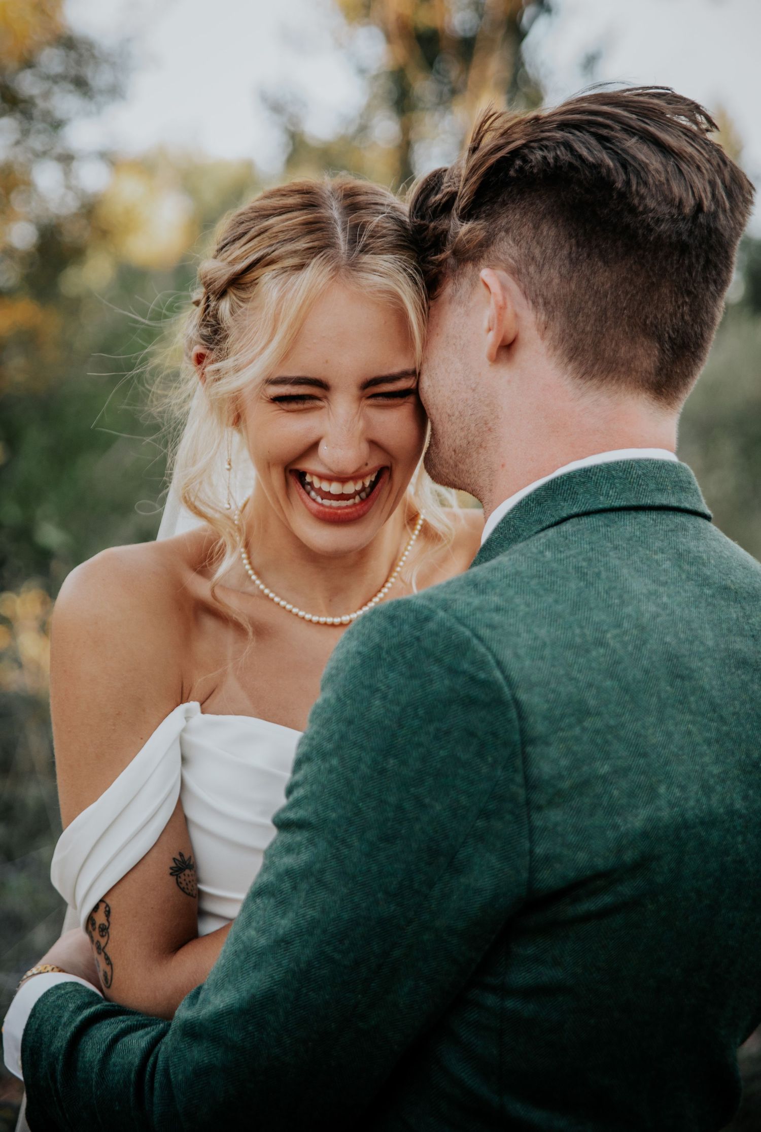 Candid laughter shared between newlyweds in outdoor setting.