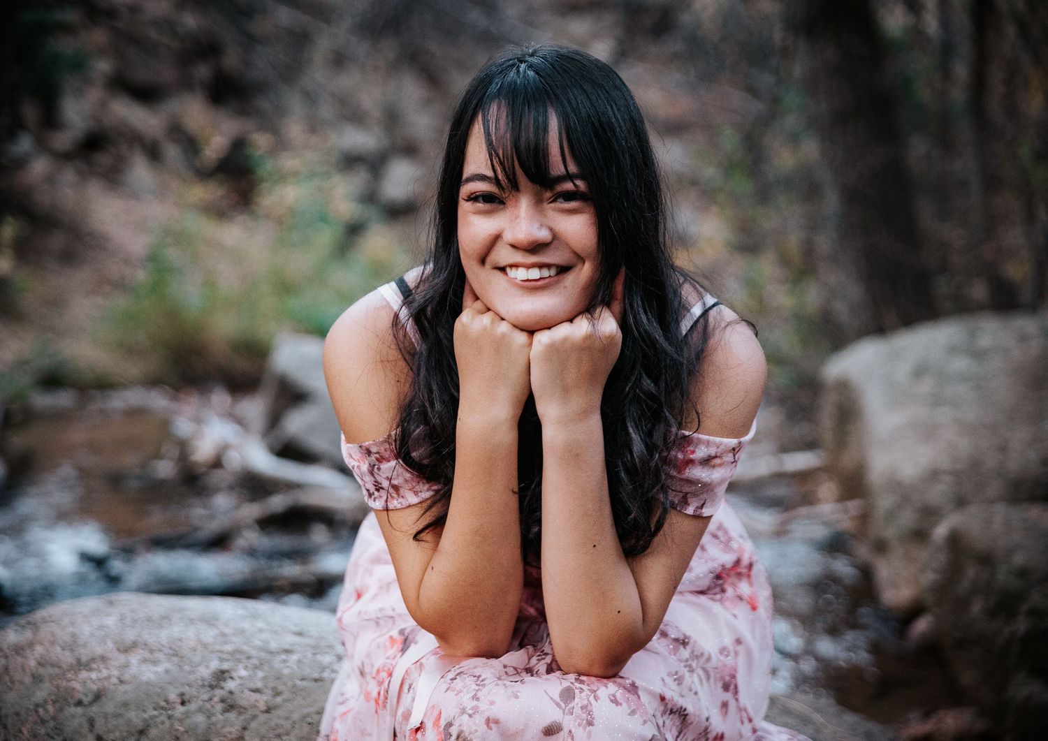 A cheerful outdoor portrait by a rocky stream.