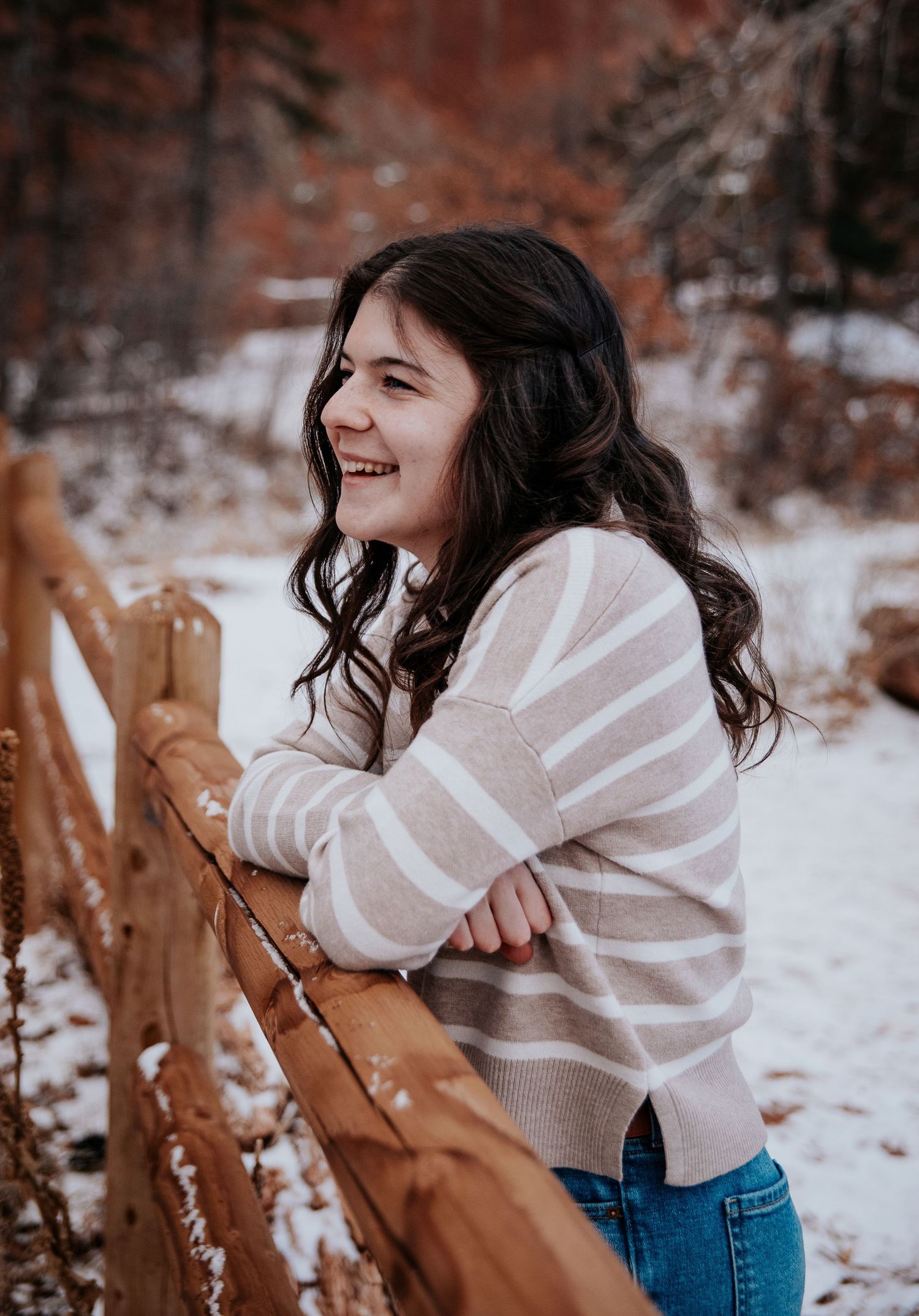 Candid laughter captured in snowy setting with wooden fence background.