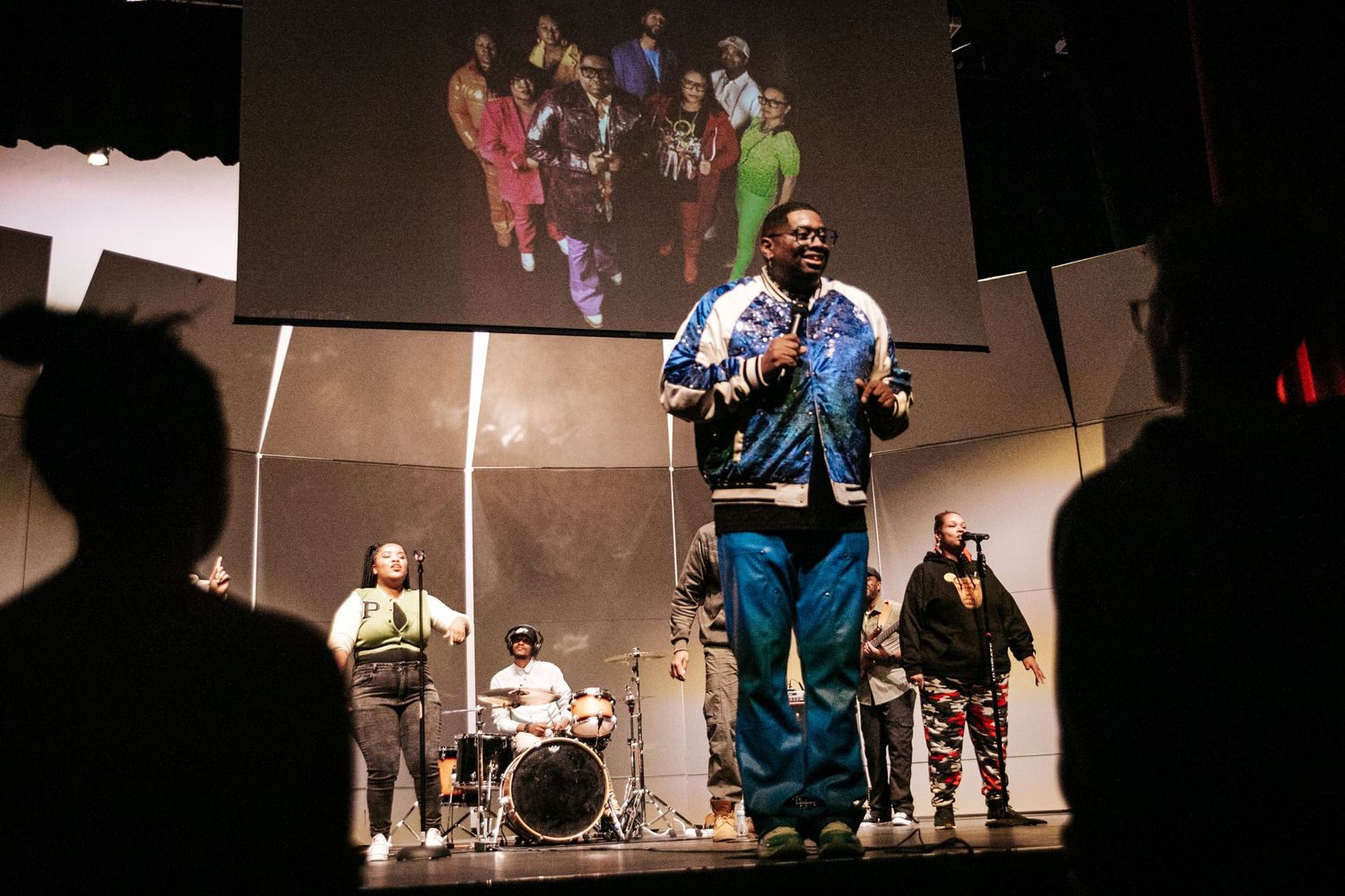Musicians performing on stage with a projected image behind them.