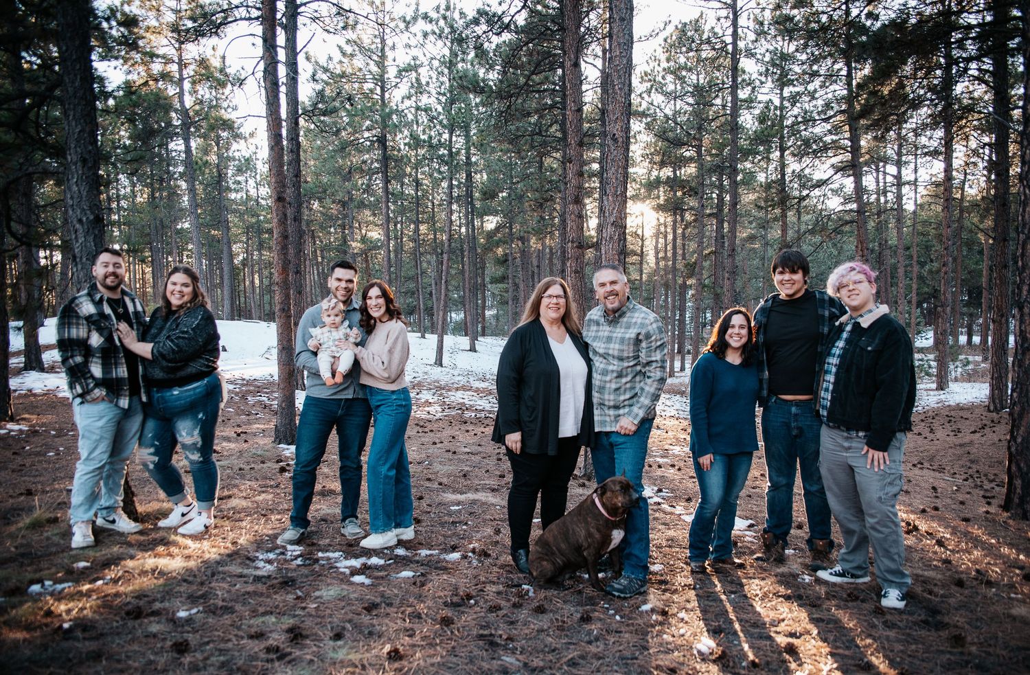 A panoramic group photo of people gathered in a snowy forest clearing.