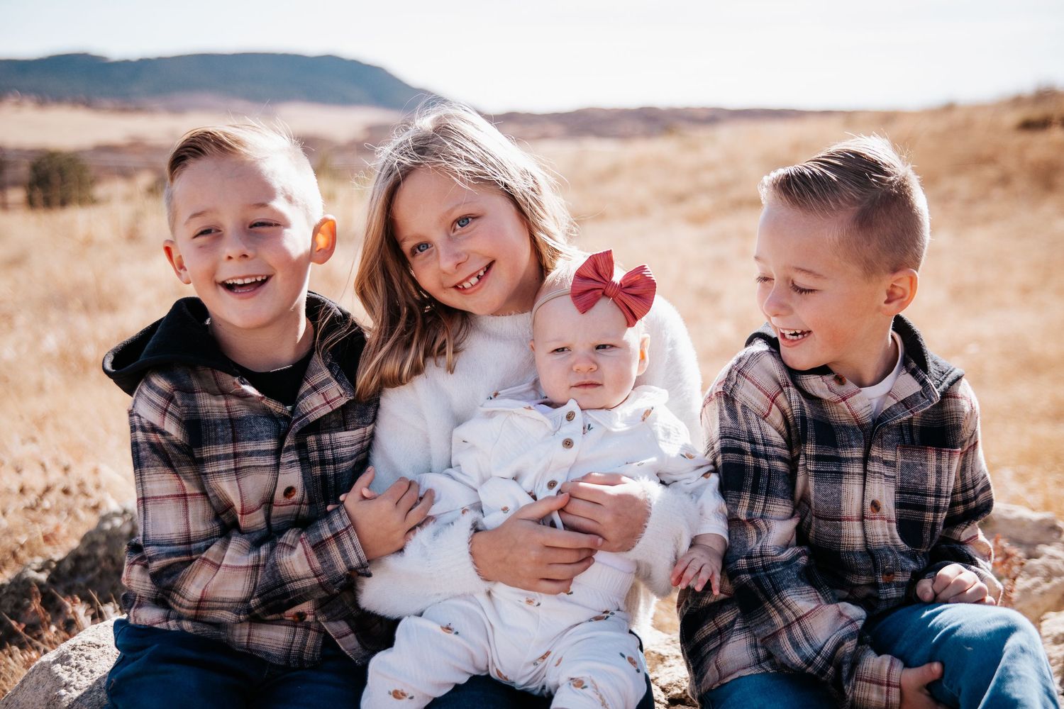 Family portrait session outdoors in a desert landscape with natural lighting and casual attire.
