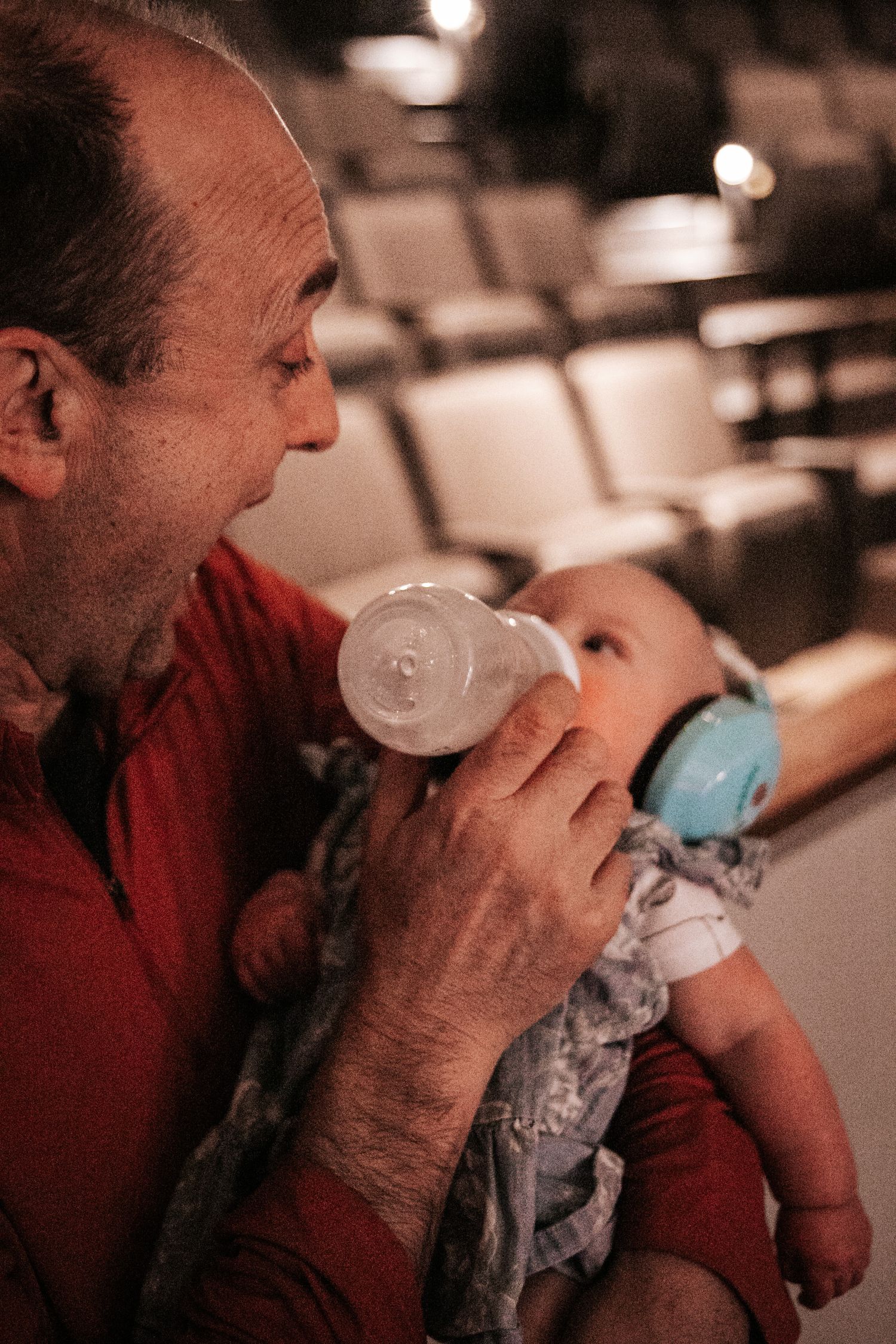 A tender moment captured as a person feeds a baby wearing blue headphones.