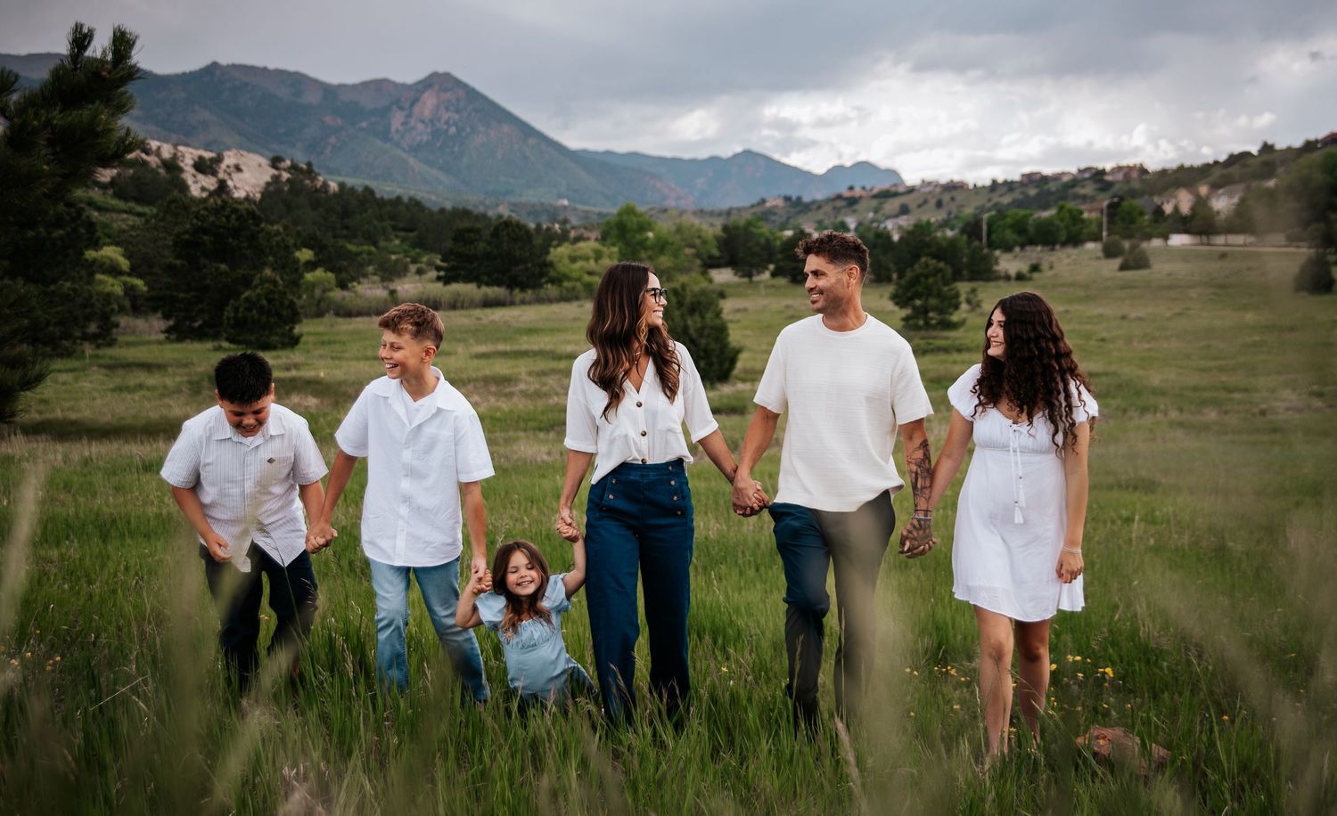 Panoramic group shot of people standing in grassy field with mountains in background at Ute Valley Park in Colorado Springs