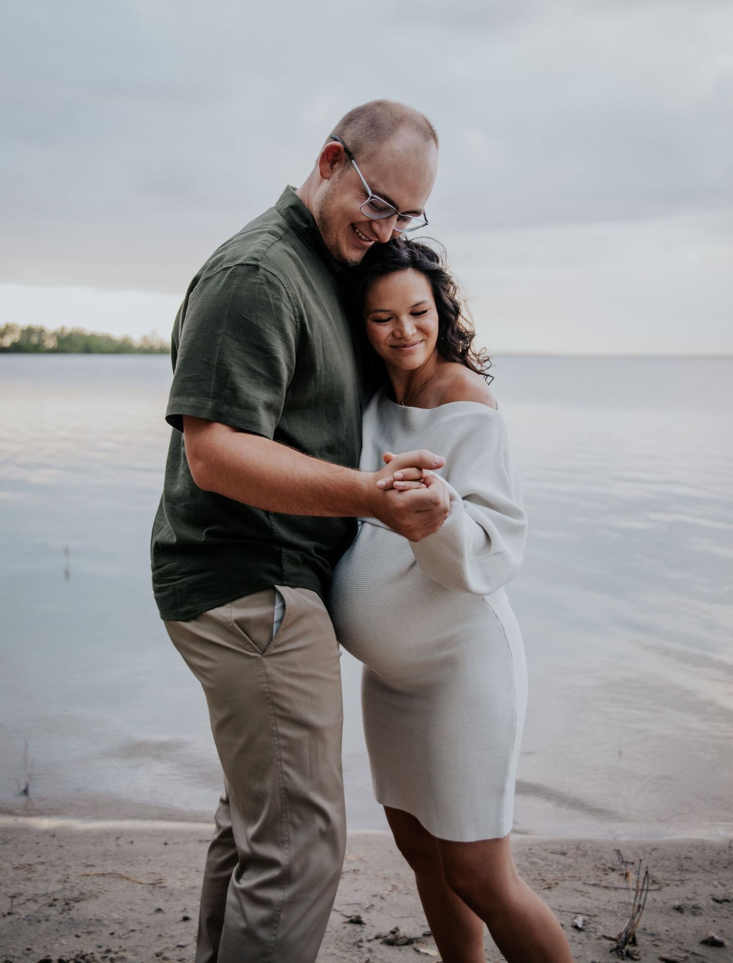 Beautiful beach maternity photos with couple sharing intimate moments by the water.