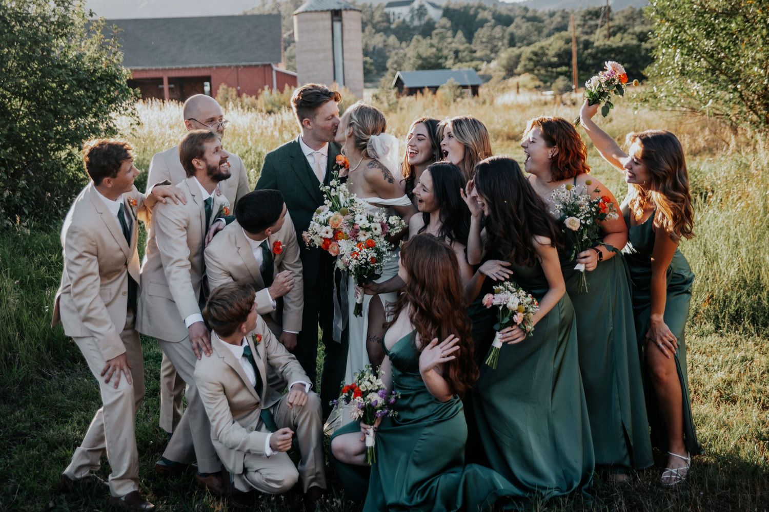 Wedding party in emerald green and beige attire gather for group photos outdoors.