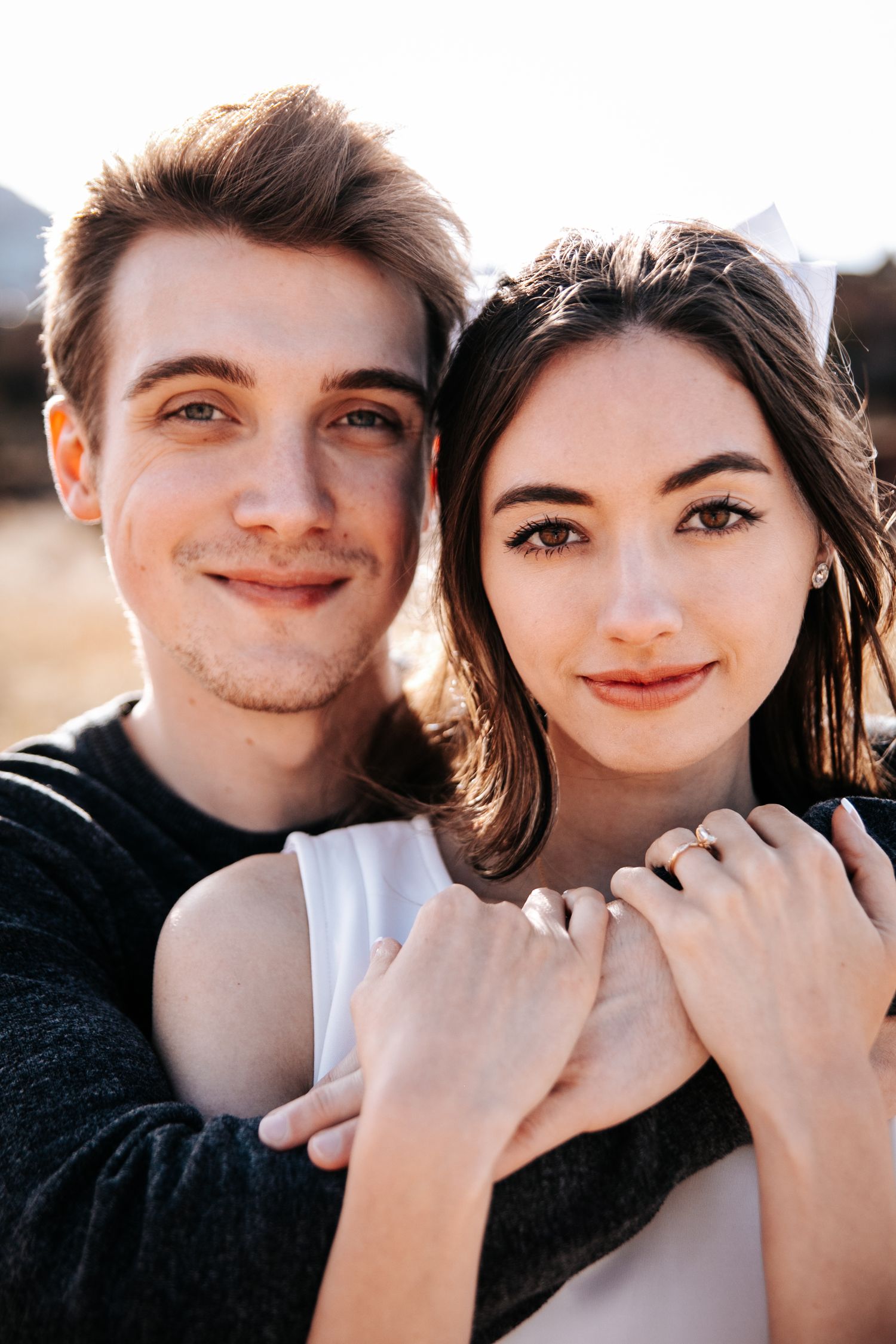 Sun-kissed portrait of couple in contrasting black and white outfits outdoors.