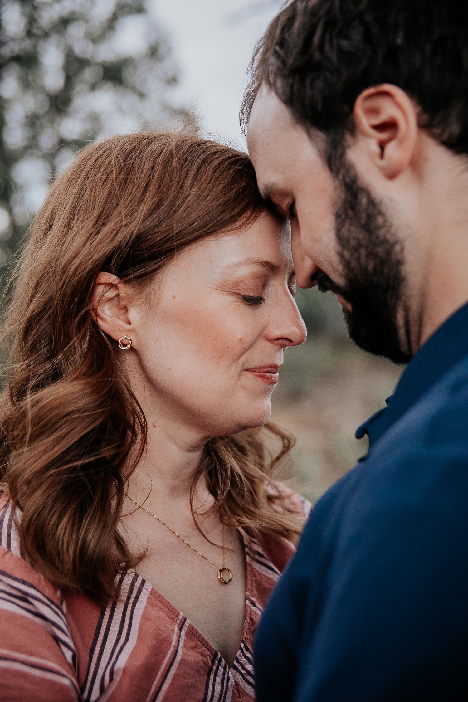 An intimate moment between a couple wearing complementary colors in an outdoor setting.