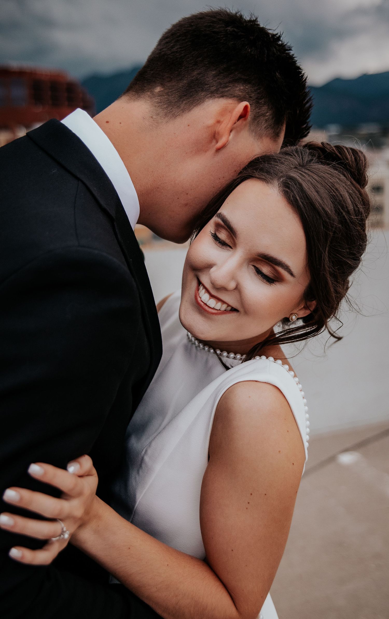 Romantic wedding portrait capturing tender moment between couple on urban rooftop.