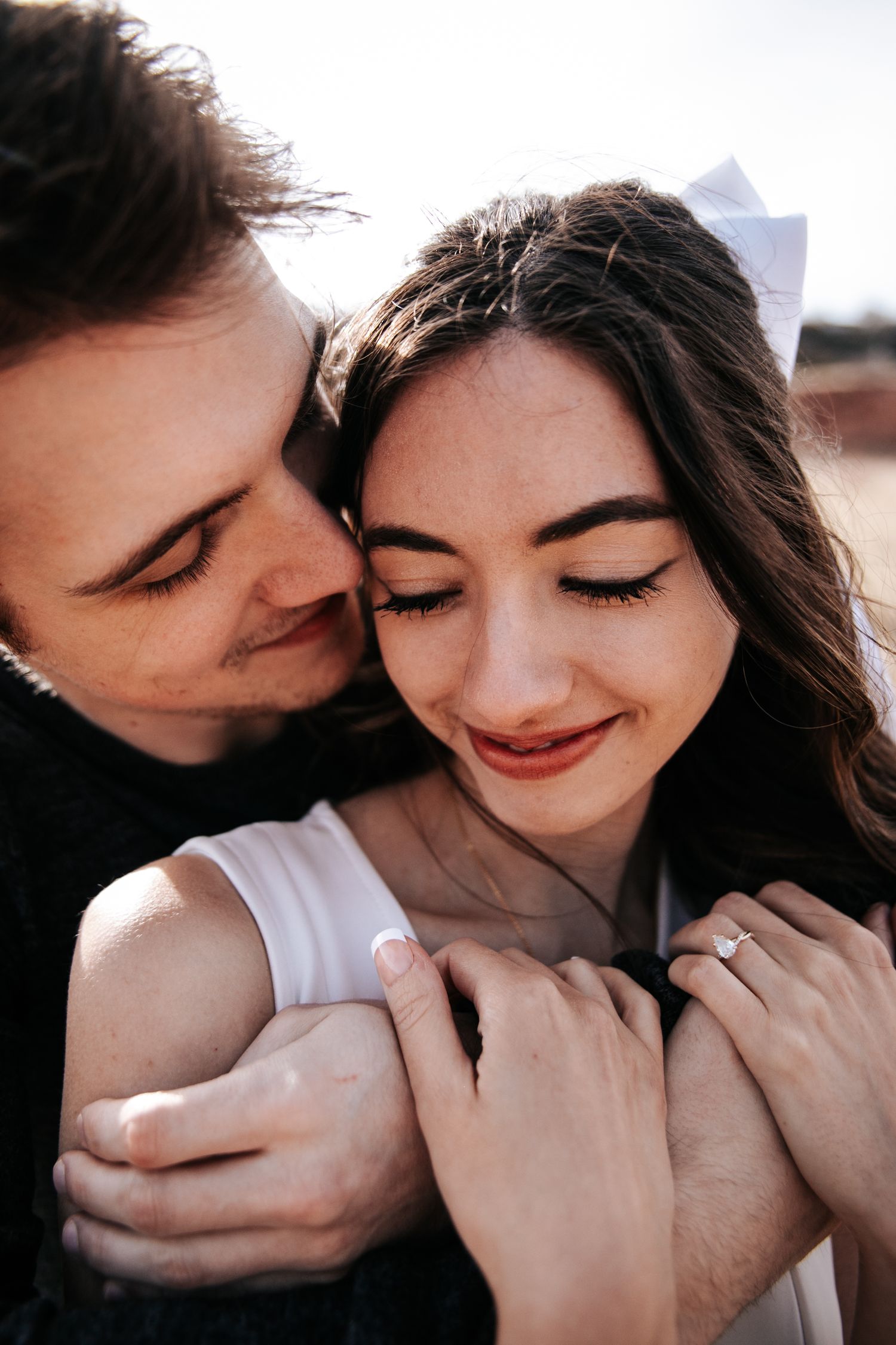 An intimate close-up portrait of a couple embracing in warm sunlight.