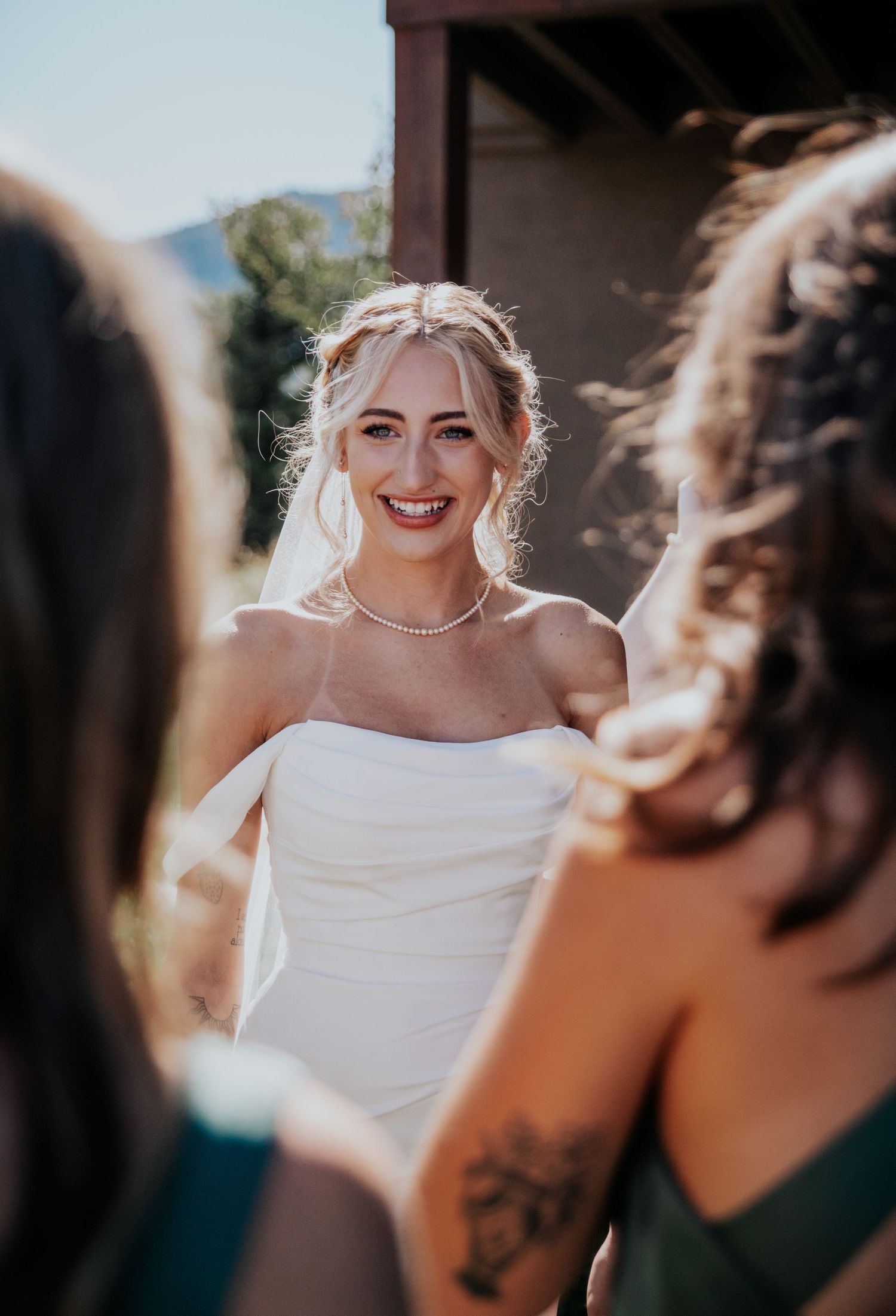 A joyful wedding moment captured in natural sunlight against a scenic mountain backdrop.