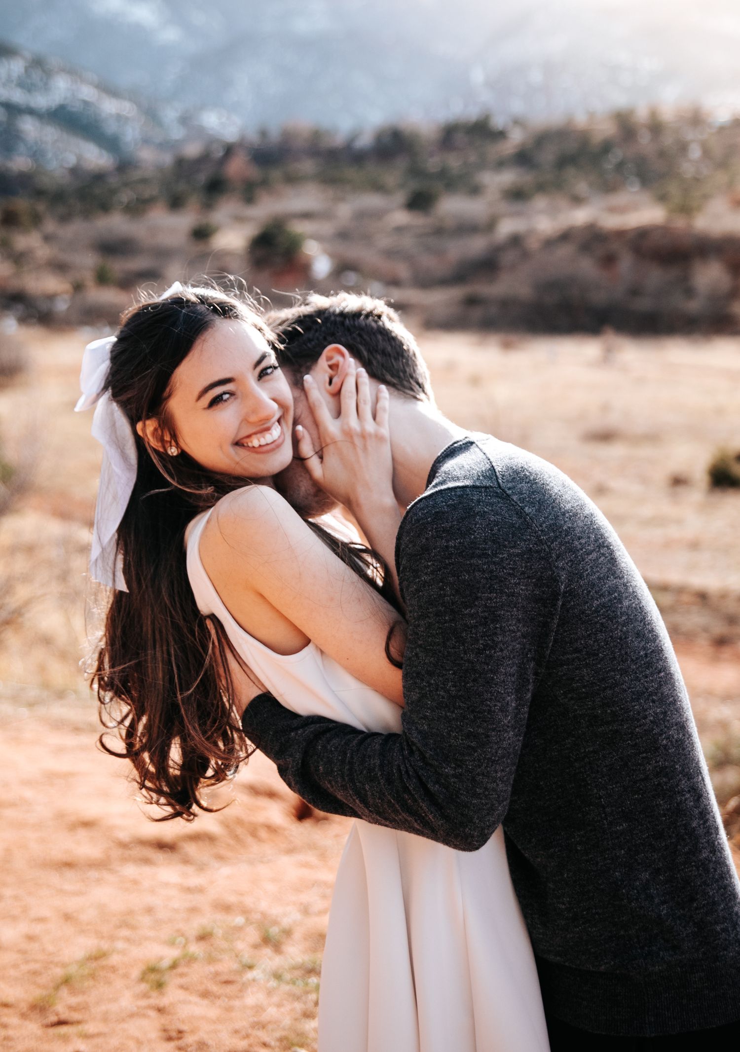 A romantic embrace captured against a mountainous backdrop.