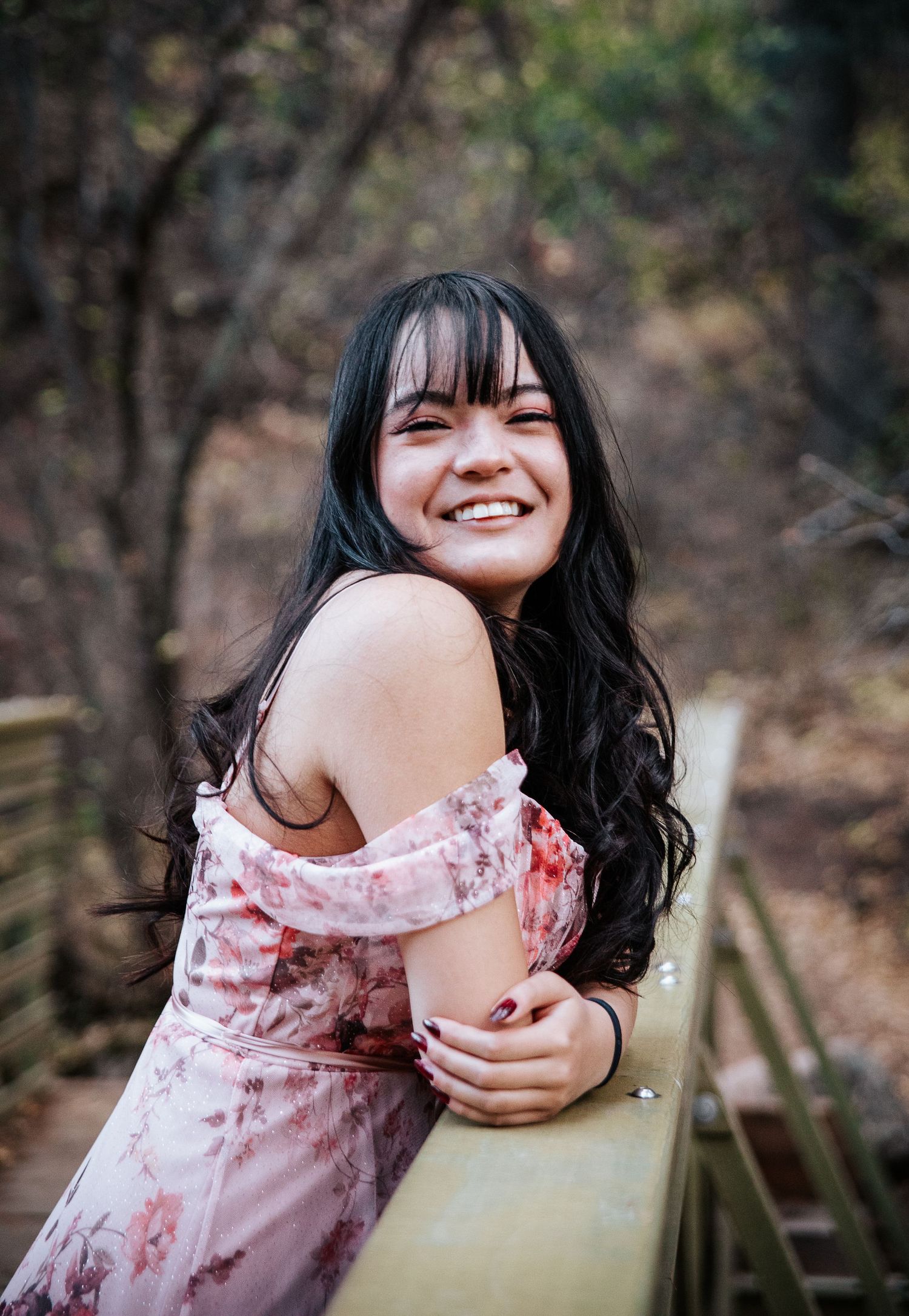 A candid portrait leaning on a wooden railing in nature.