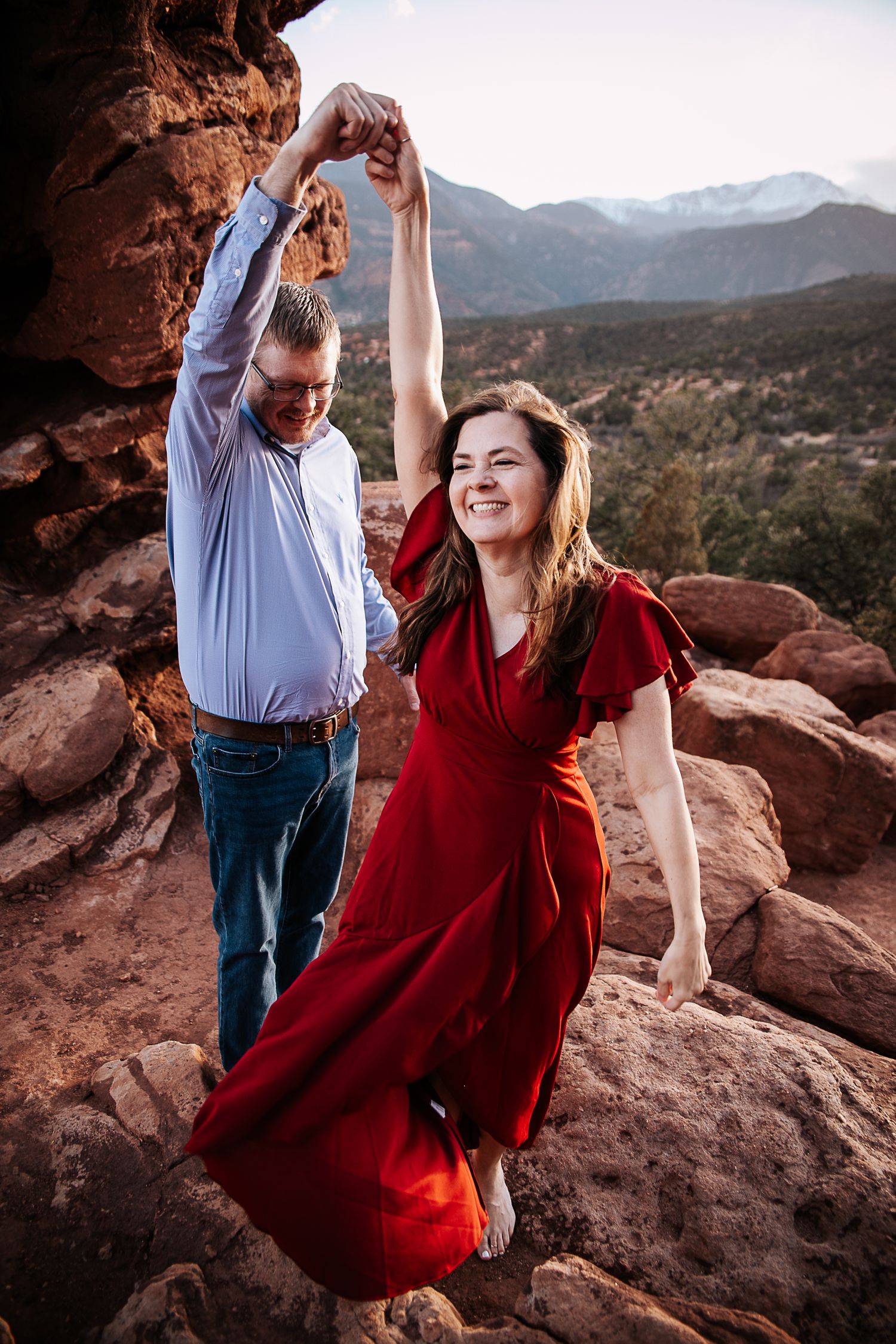 A joyful dancing moment captured on red rocks with mountain views.