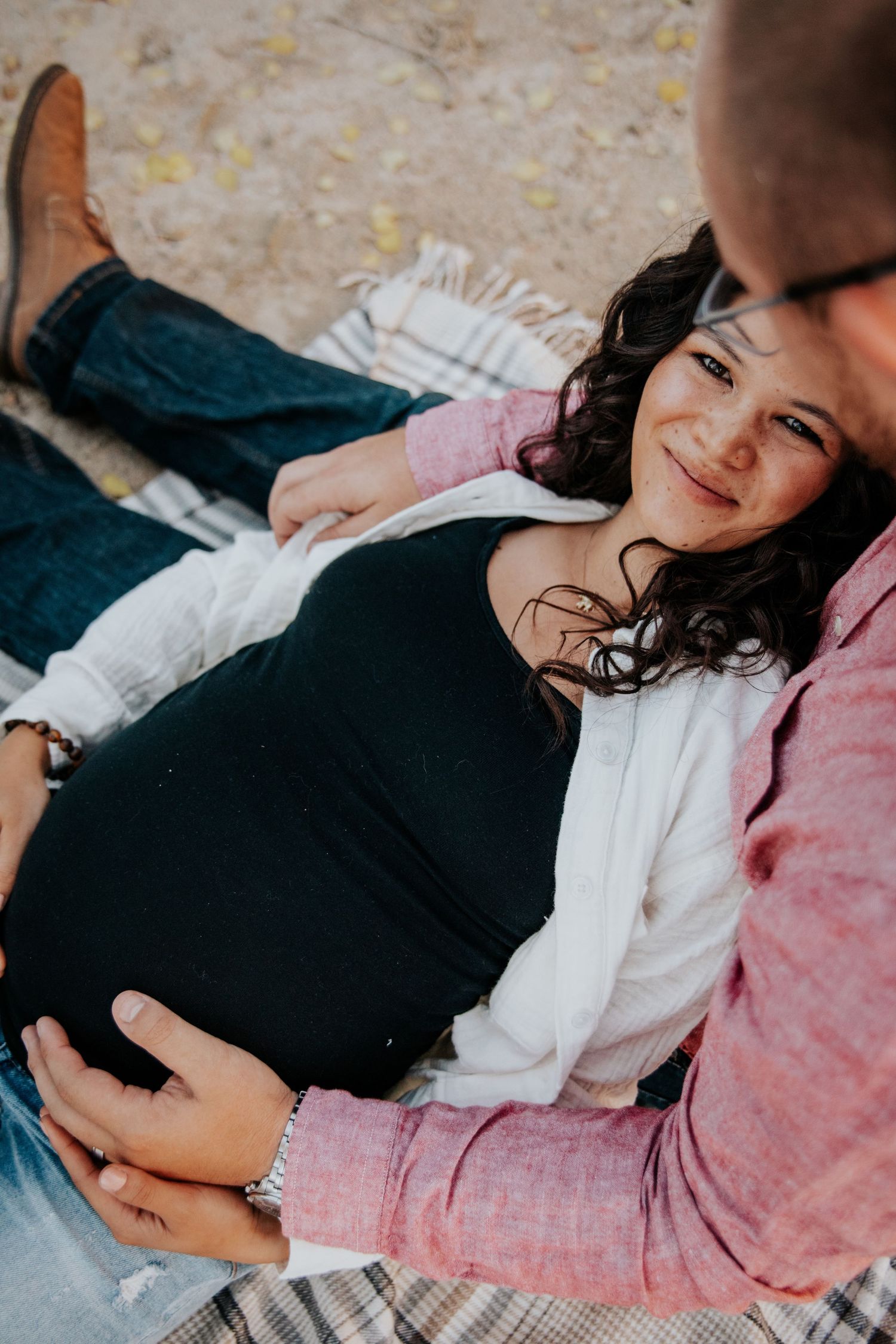 Wife laying on husband's lap during maternity photo session in Colorado Springs
