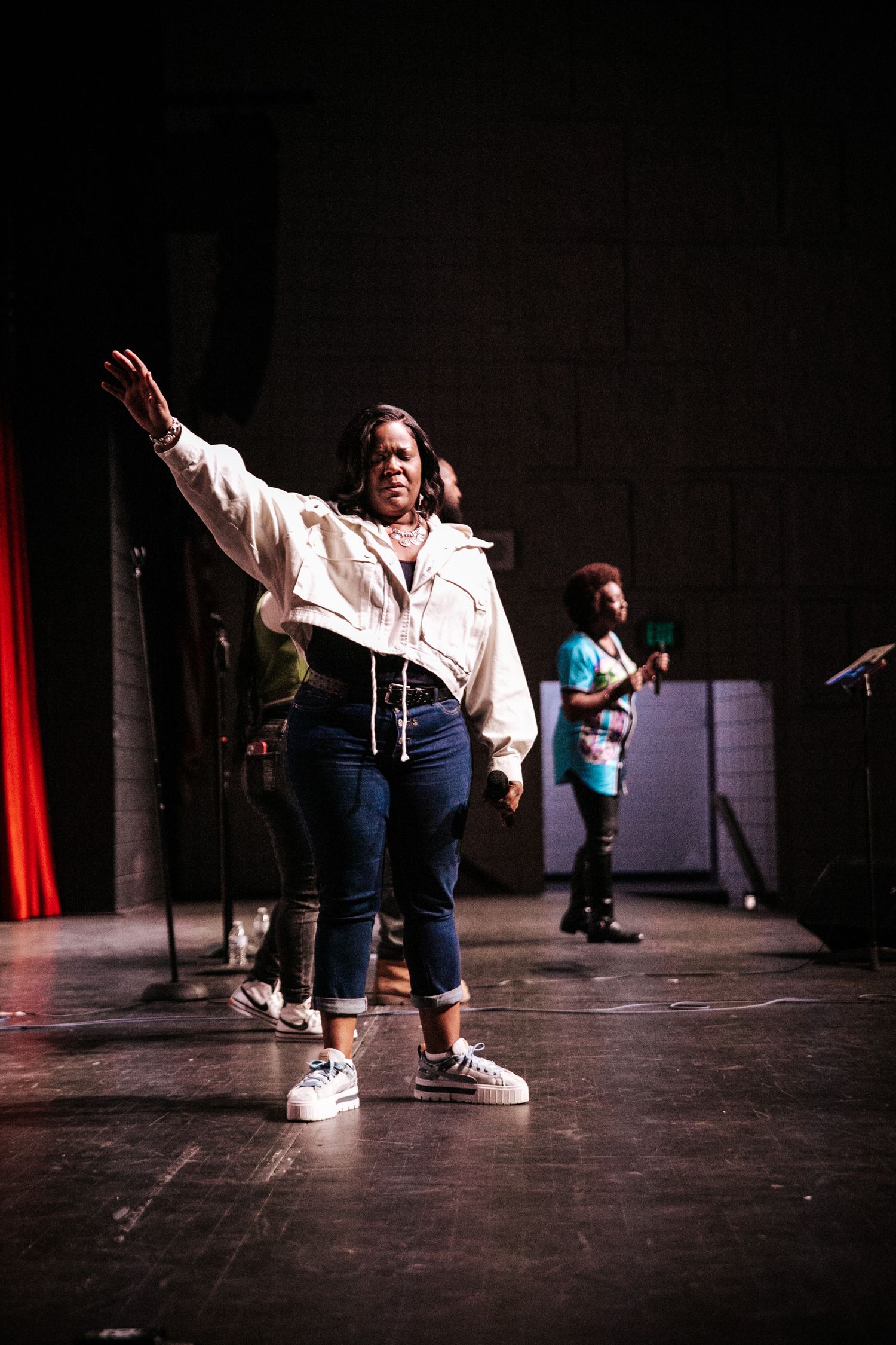 Performers in casual clothing dancing on a dark stage floor.