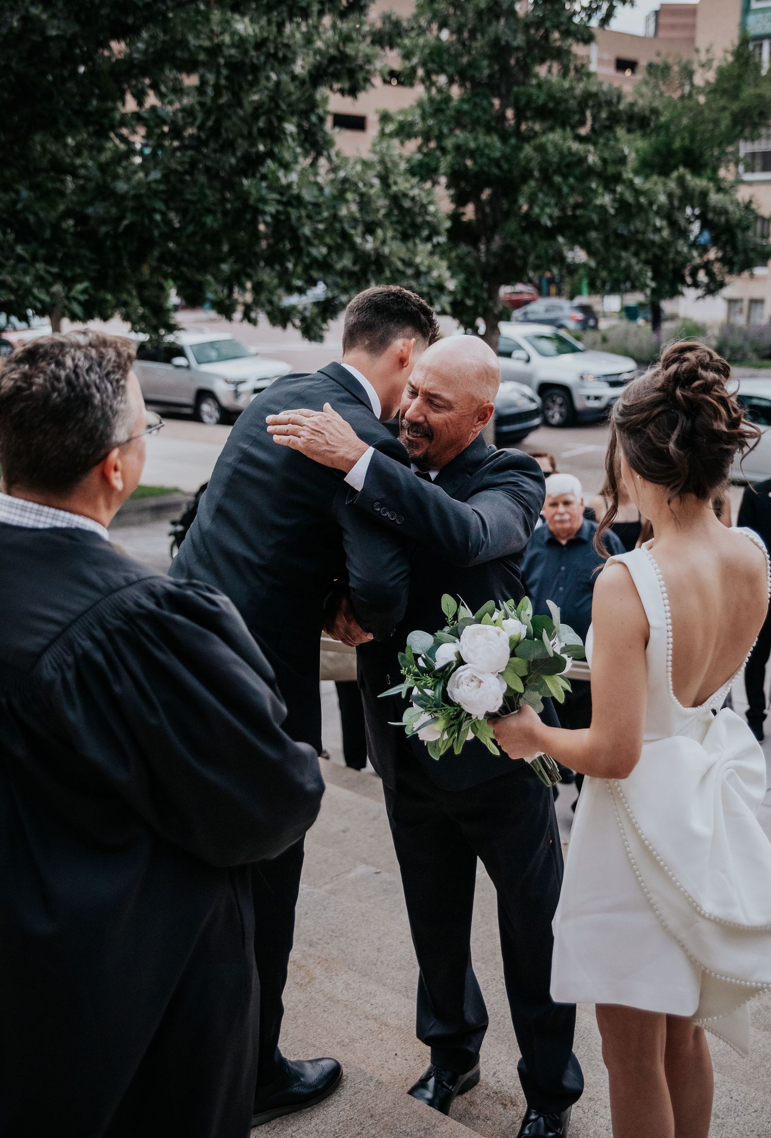 Wedding party celebrates with playful poses and interactions outdoors.