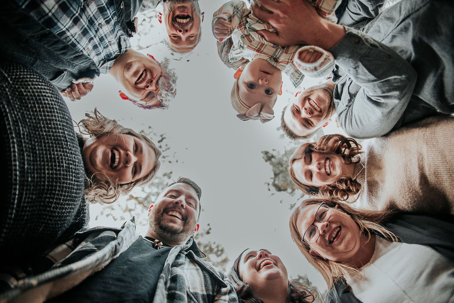 Group photo taken from below showing smiling faces in a circle formation.