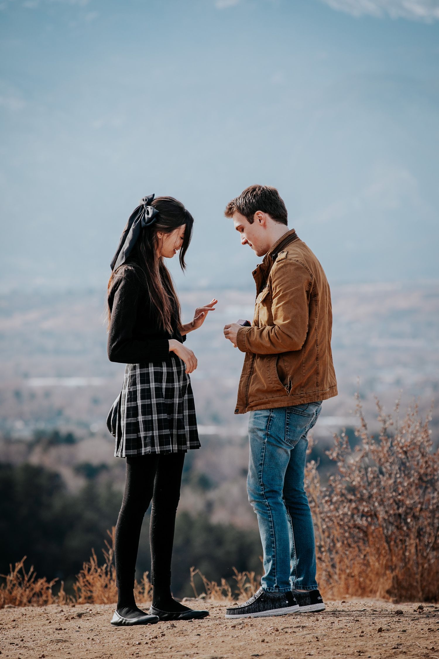 Couple examining engagement ring together on mountaintop after proposal.