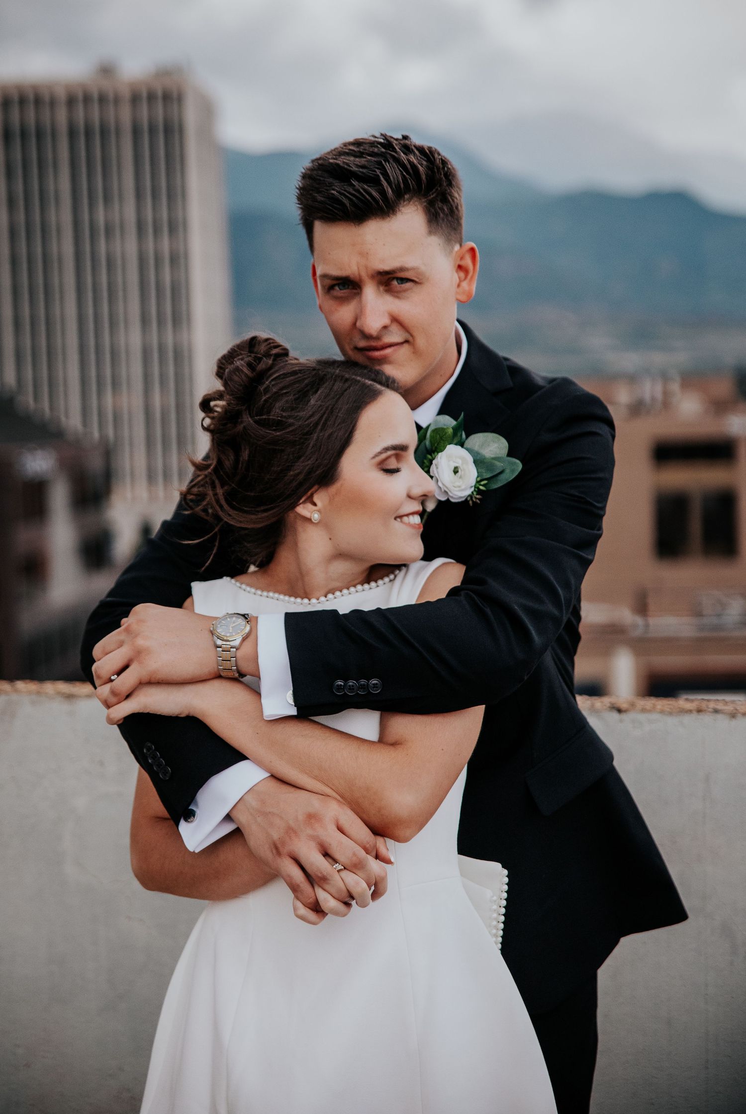 Wedding couple embracing in a series of candid moments on a rooftop with city views.