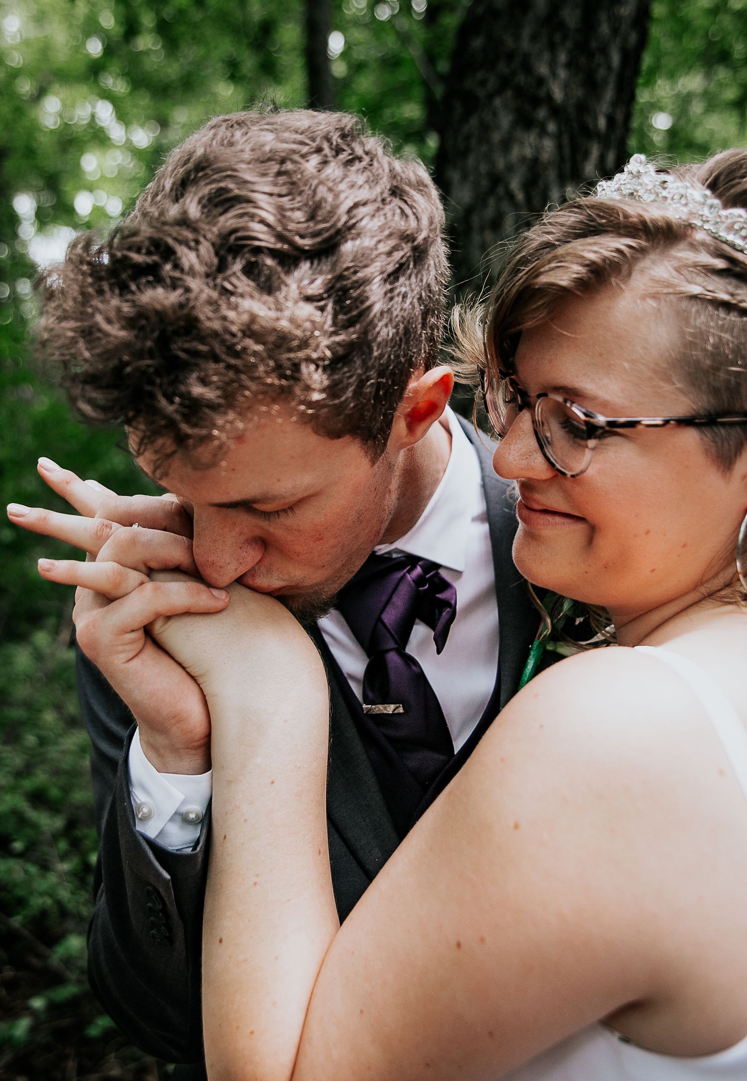 An intimate wedding moment captured in a sunlit forest setting.